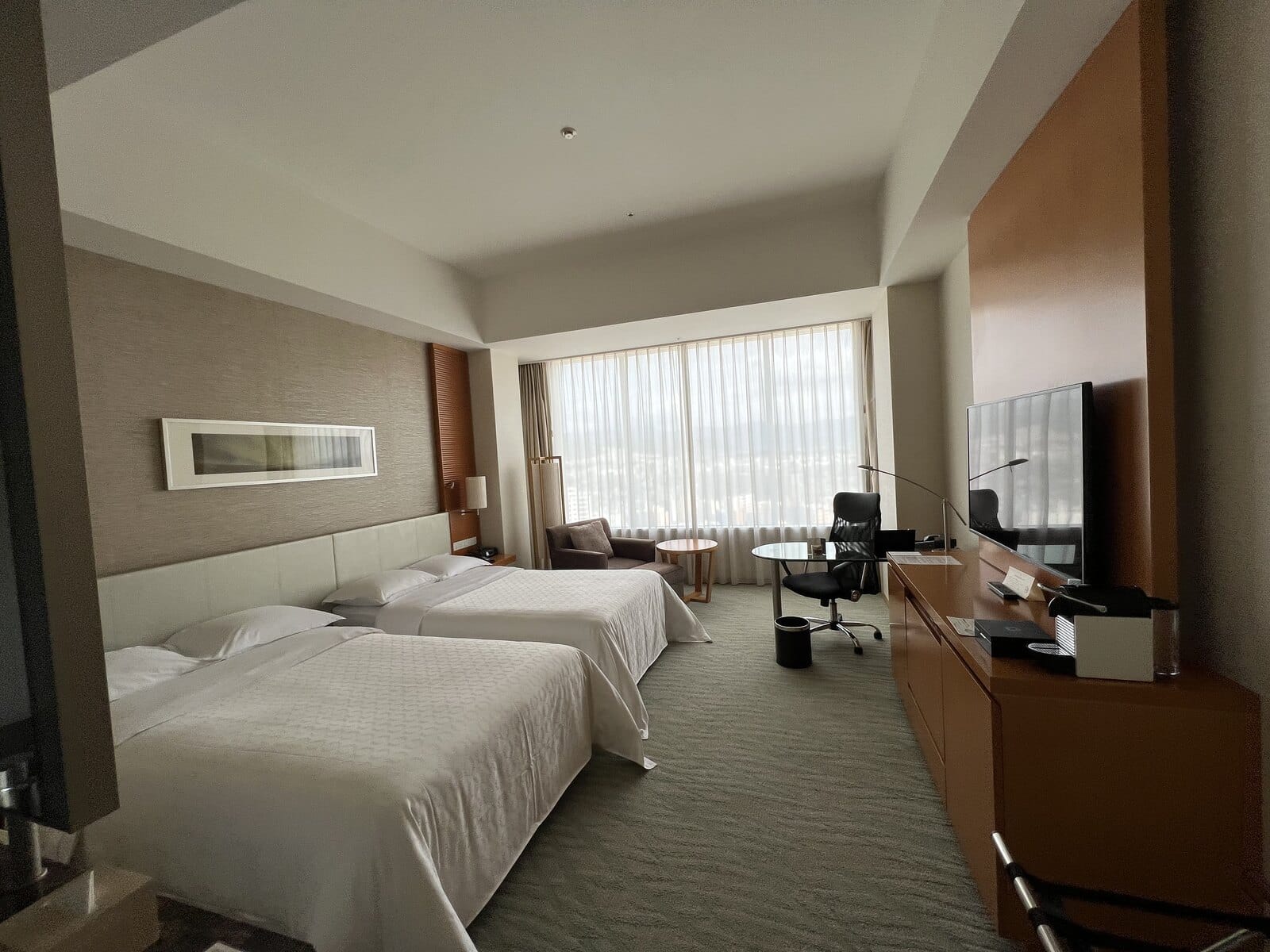 Twin hotel room in Hiroshima with large windows and a work desk
