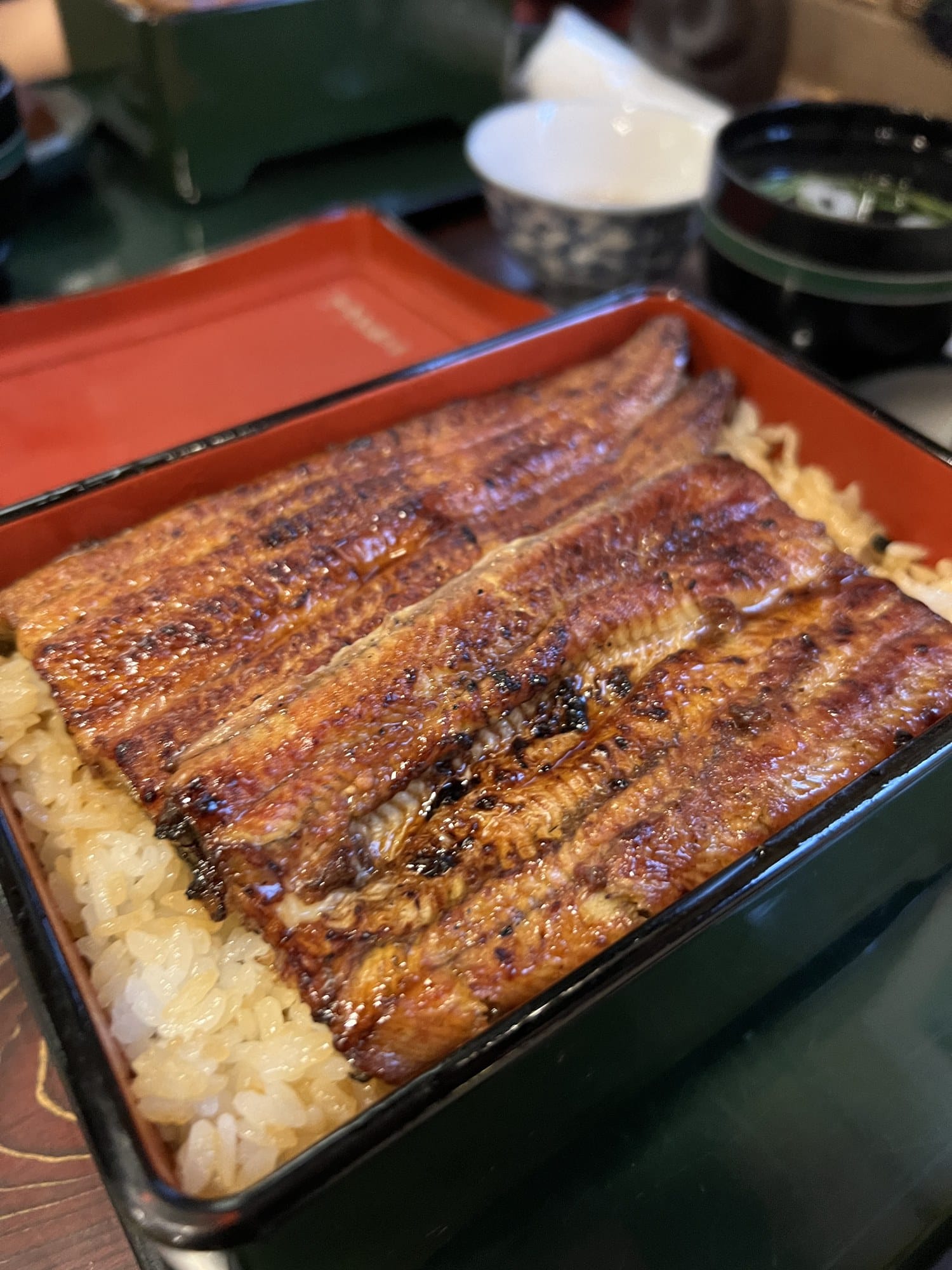 Glazed grilled eel fillets covering a lacquered box of rice at Kanda Kikukawa near Akihabara
