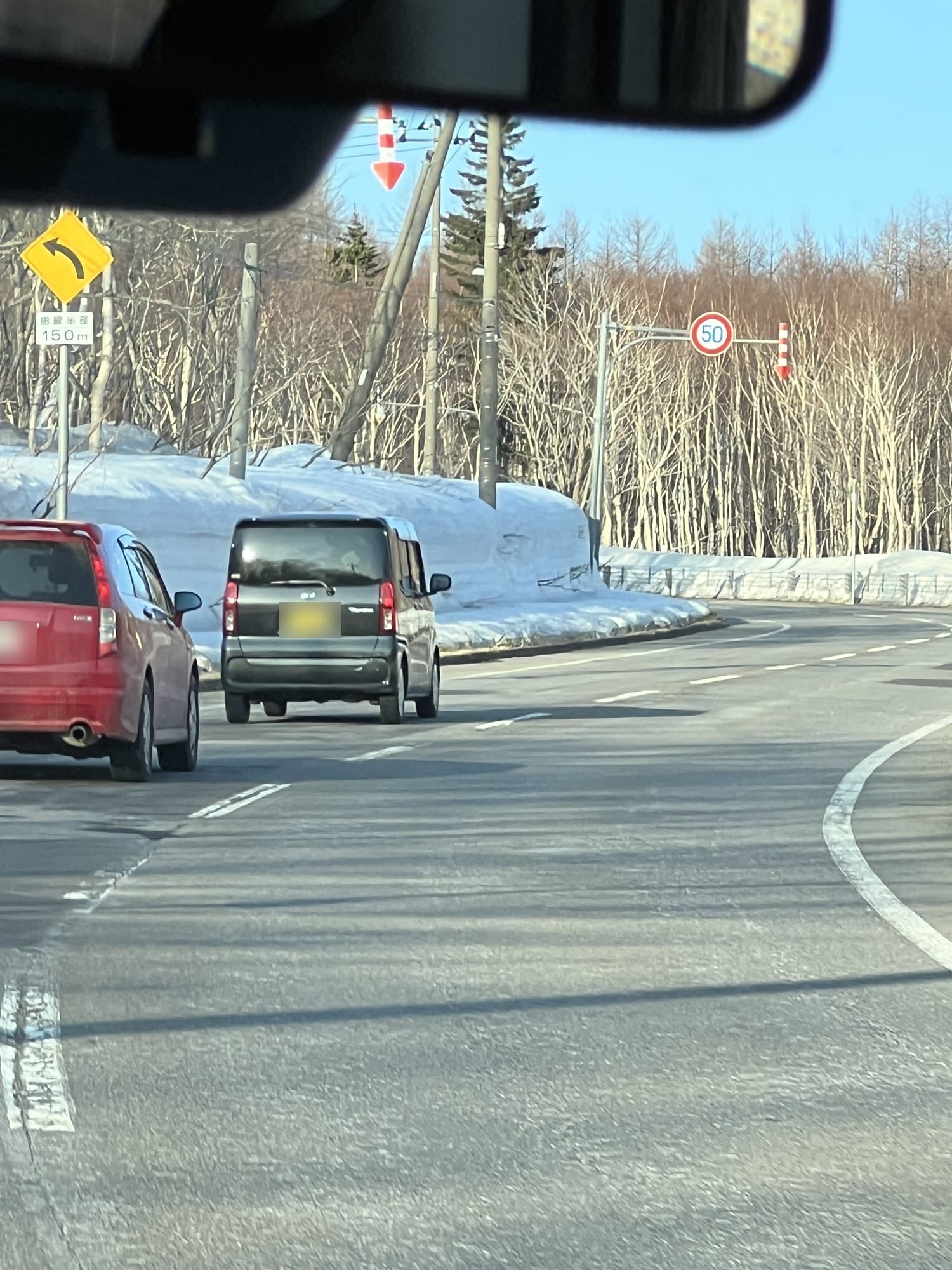 Bitume sec sur la route de Kiroro en fin de saison, congères encore présentes en bord de route