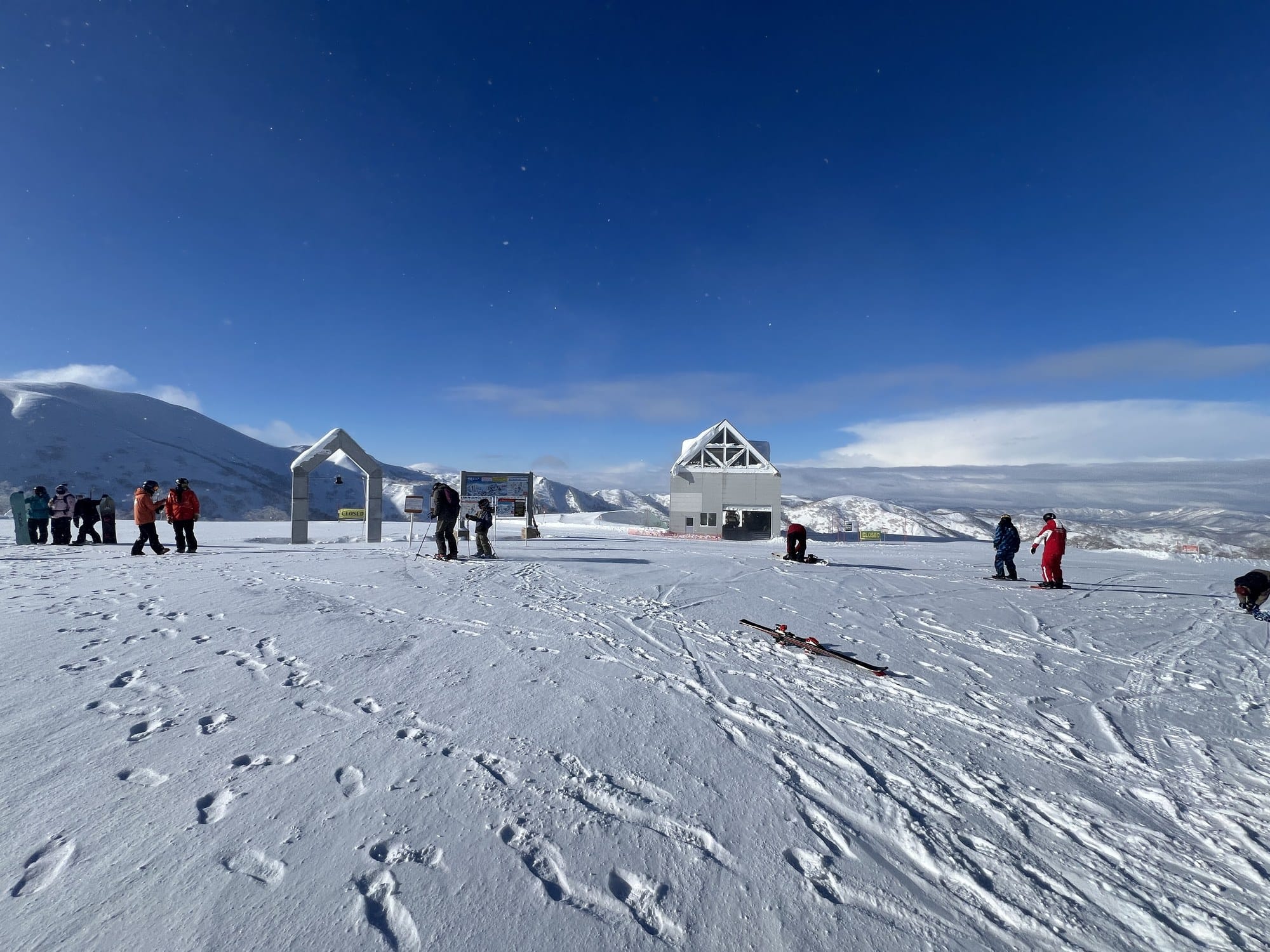 The Kiroro summit gondola station and peace bell arch under a deep blue sky, with fresh tracks in the snow