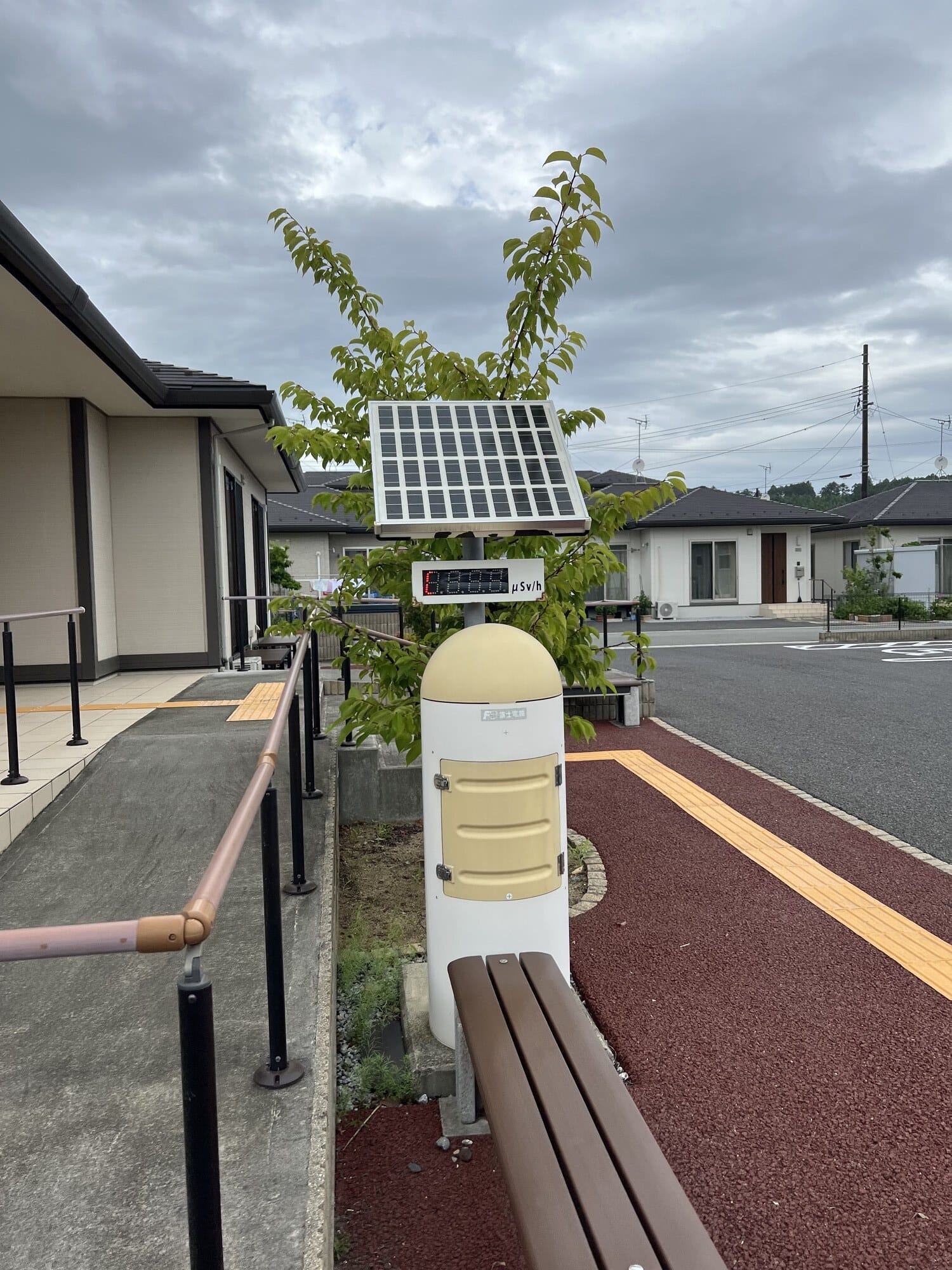 Radiation monitoring post with solar panel and digital display on a residential street in Tomioka, Fukushima