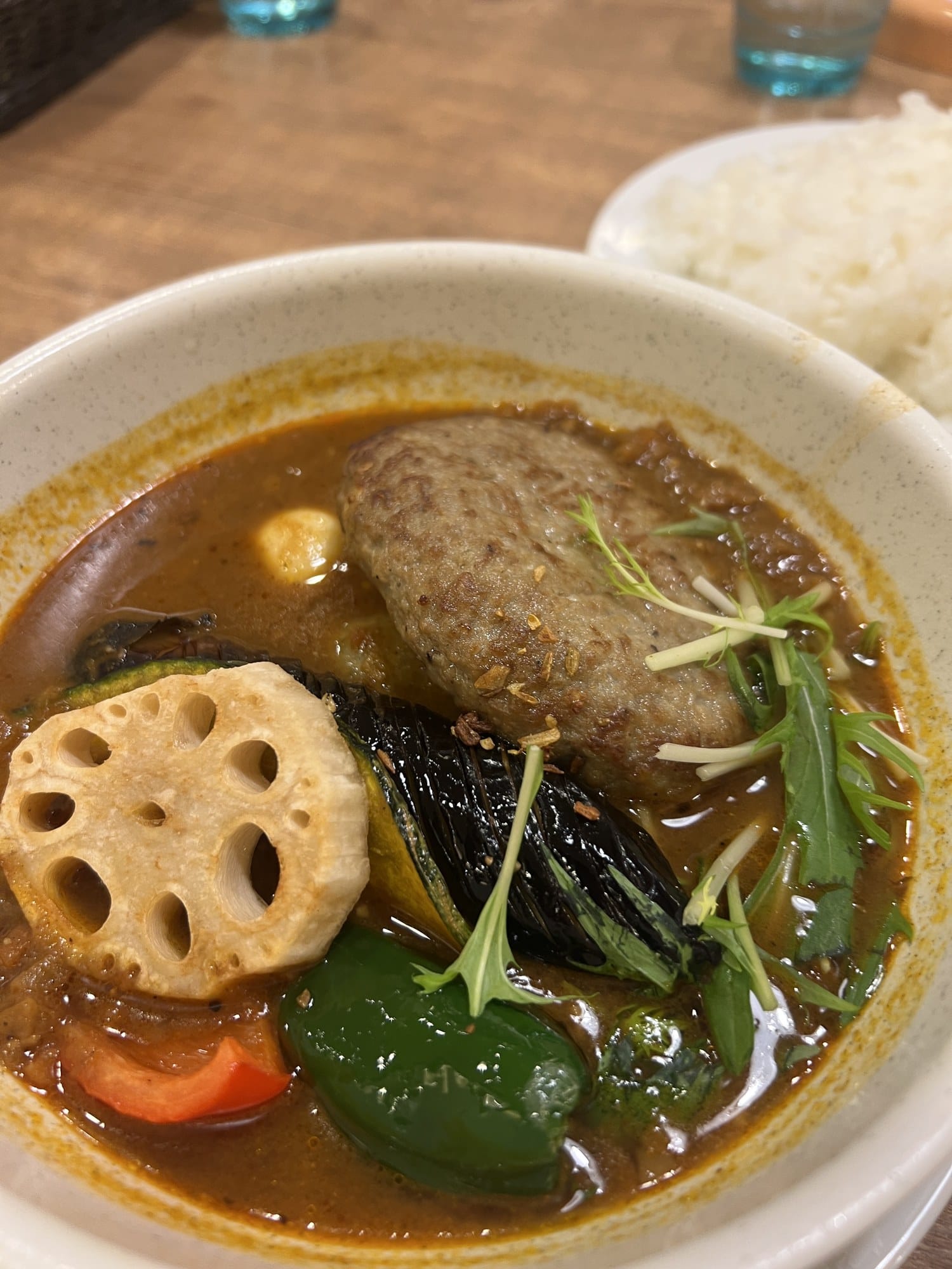 A bowl of Hokkaido soup curry with a lamb patty, lotus root and vegetables