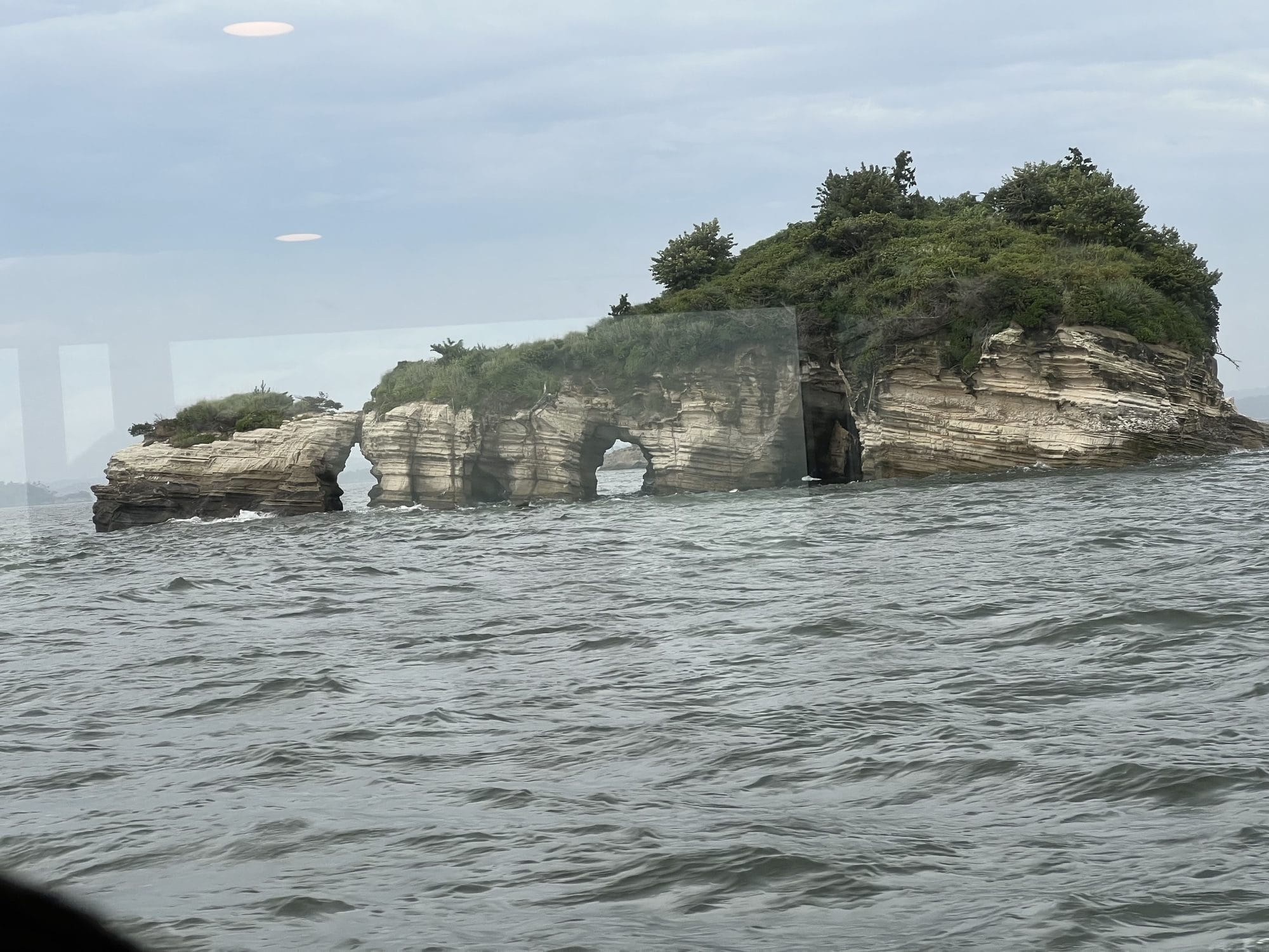 Rocky limestone island with natural sea arches rising from Matsushima Bay, viewed from the water
