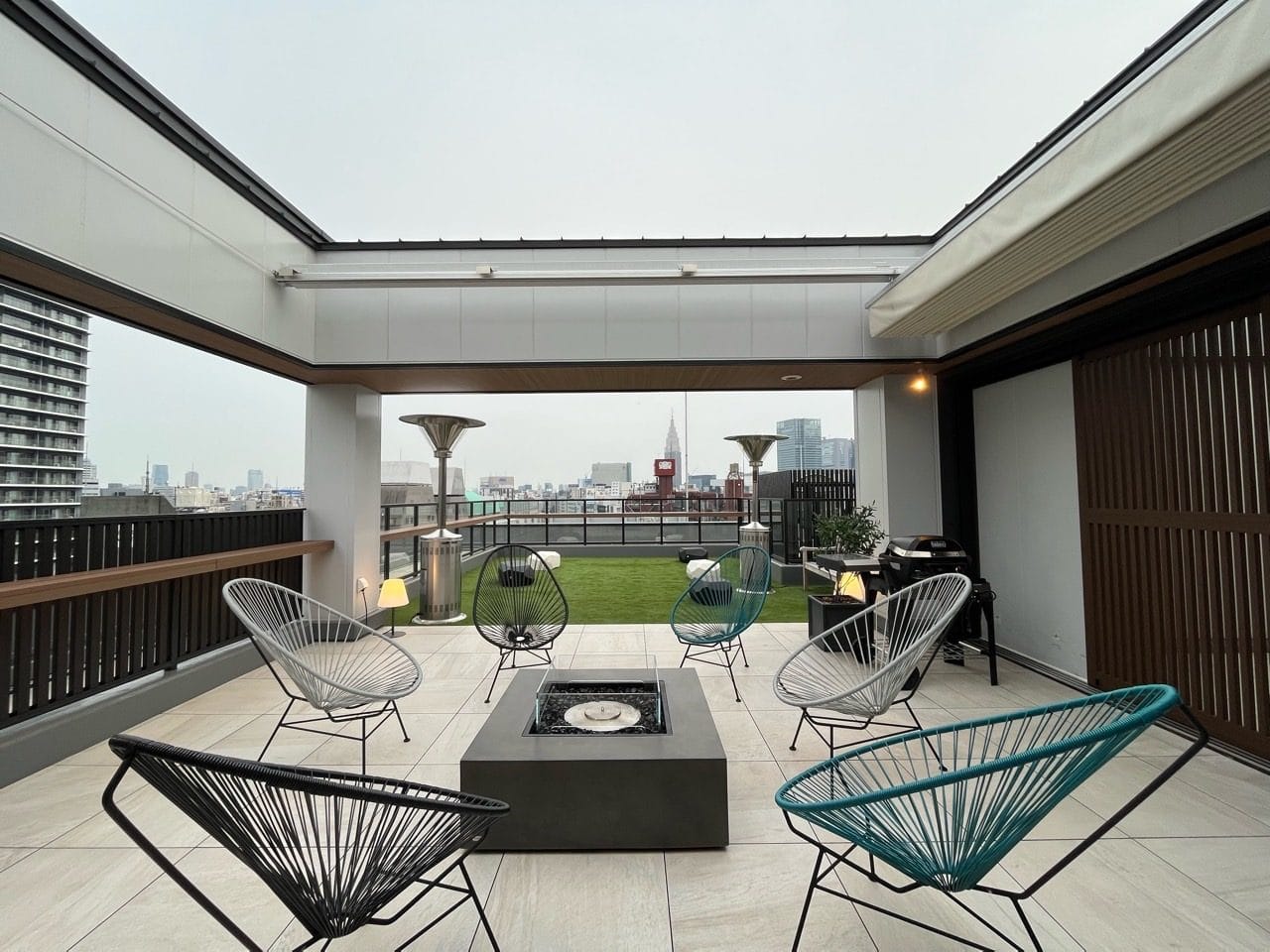 Rooftop terrace lounge at a Shinjuku hotel with outdoor seating, fire pit, and city skyline views