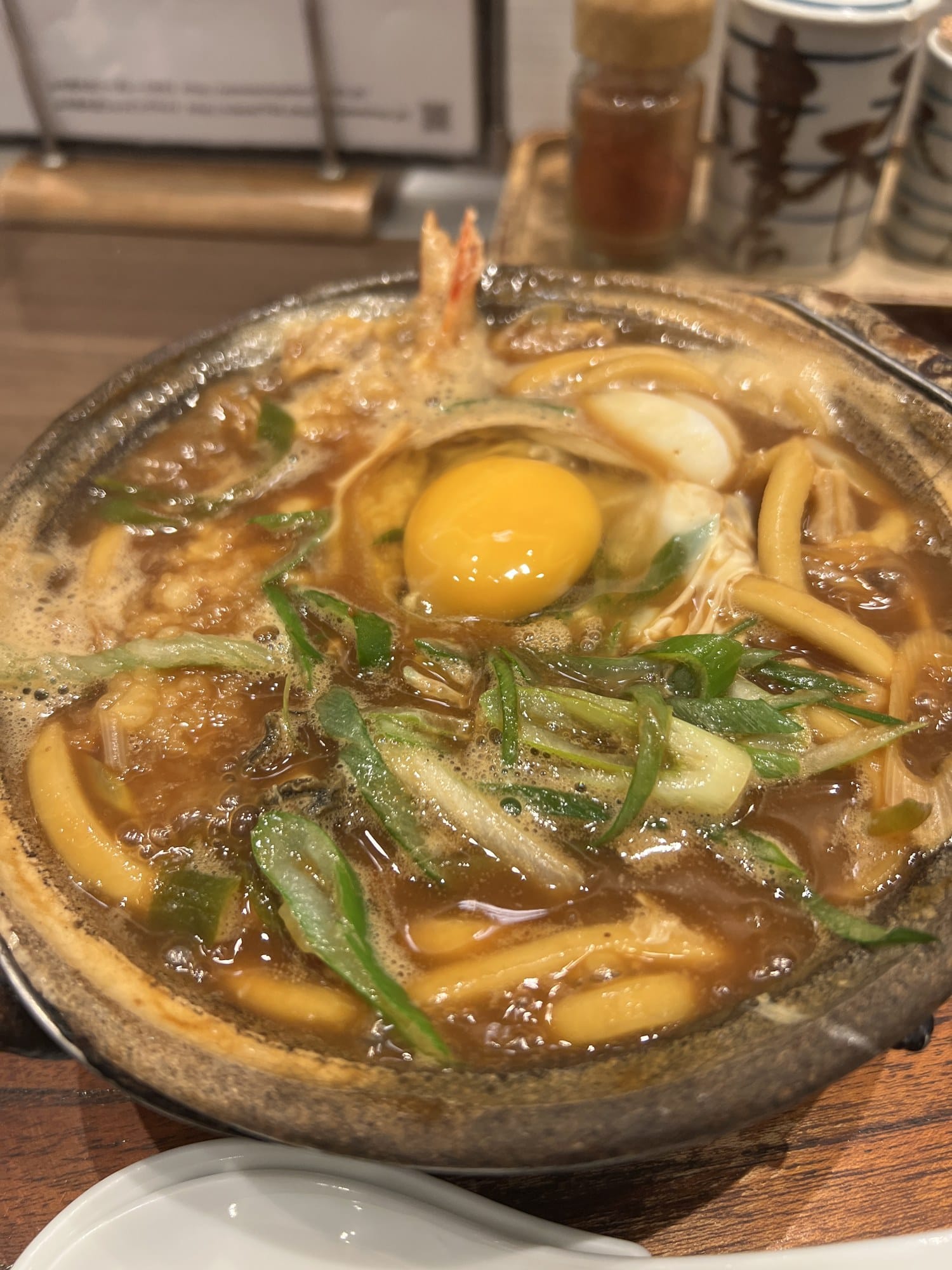 Yamamotoya Honten misonikomi udon in a clay pot with a raw egg yolk, shrimp tempura and green onions