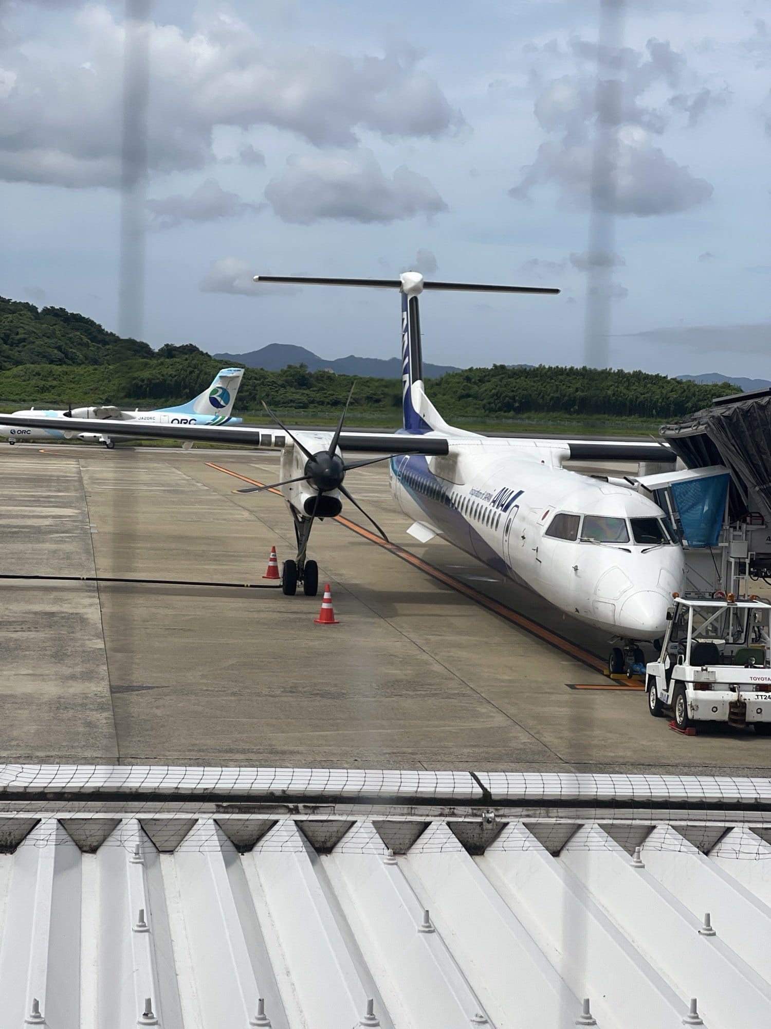 An ANA Bombardier Q400 at a regional gate with an Oriental Air Bridge turboprop parked behind