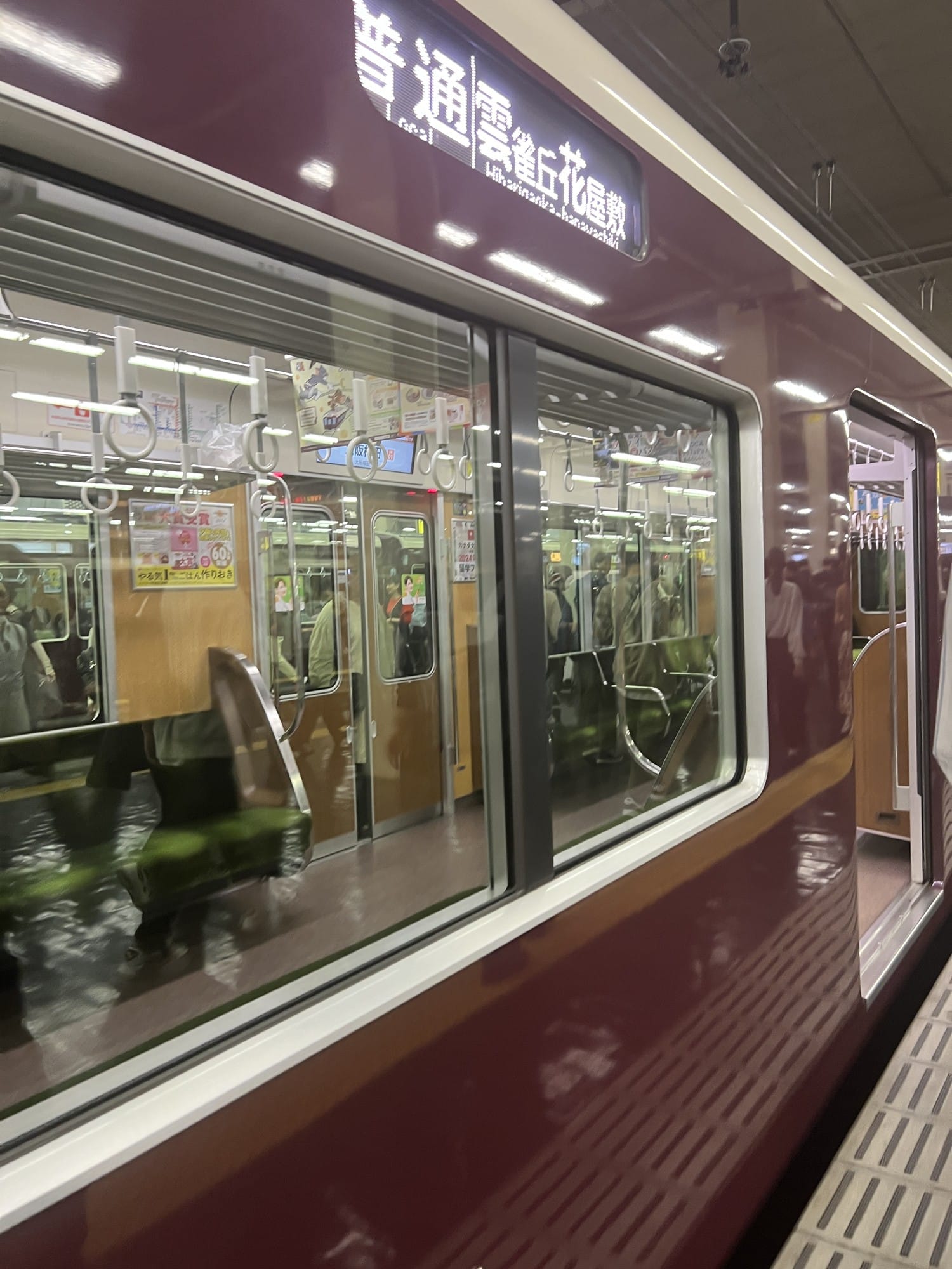 Maroon Hankyu commuter train at a platform with a local service destination display