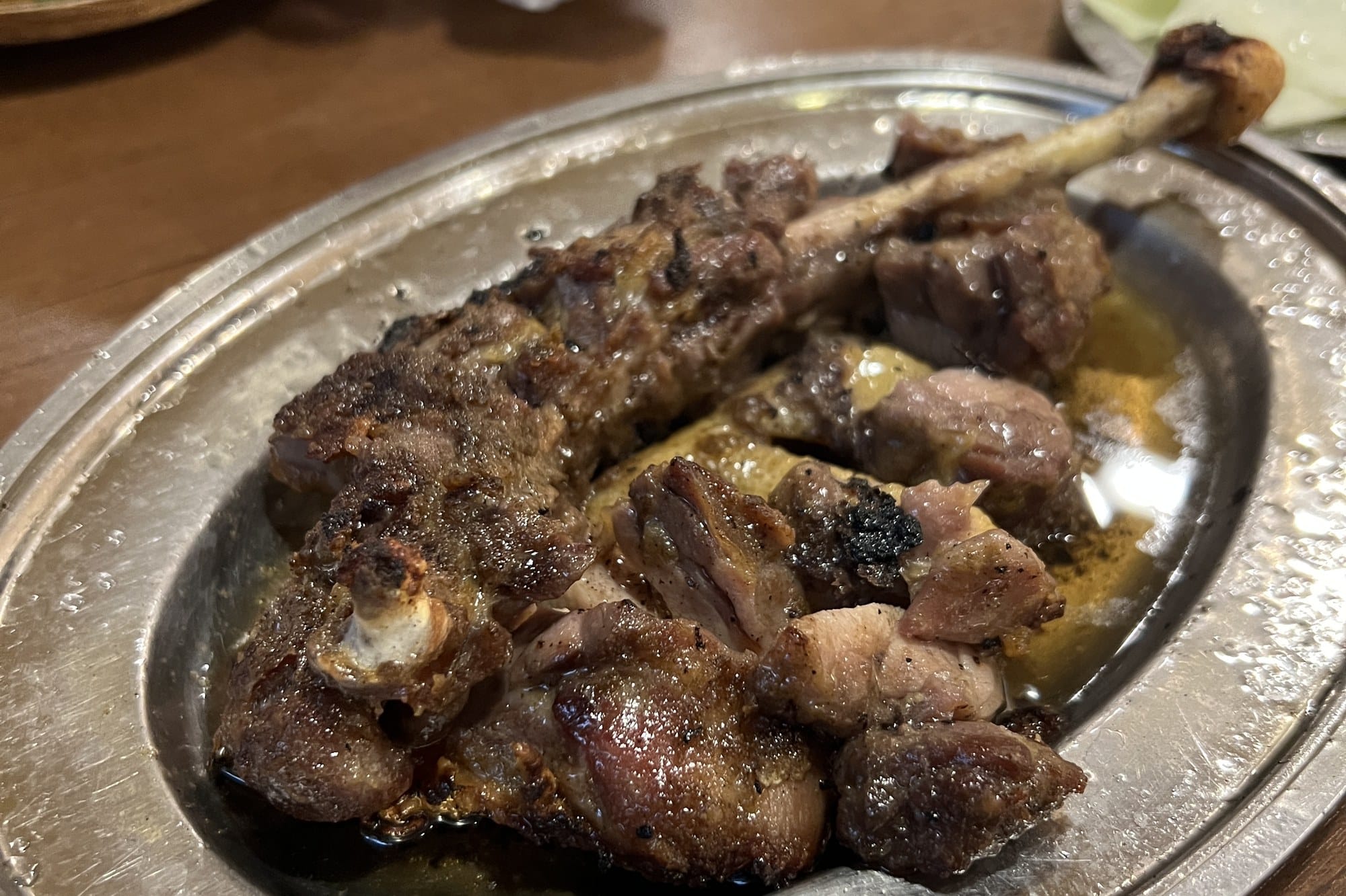 Honetsukidori, bone-in grilled chicken legs on a metal plate, served with edamame