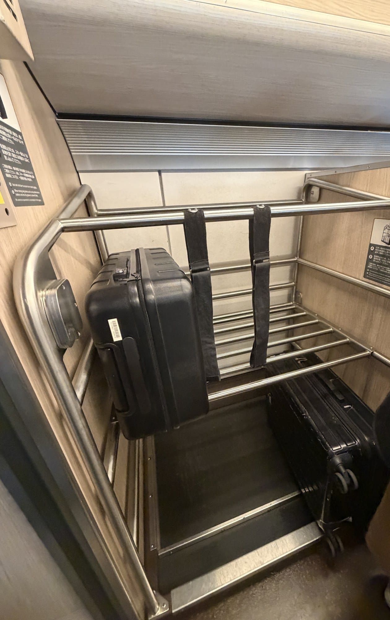 Belt-strap oversized luggage rack on board a Tohoku Shinkansen train holding two suitcases