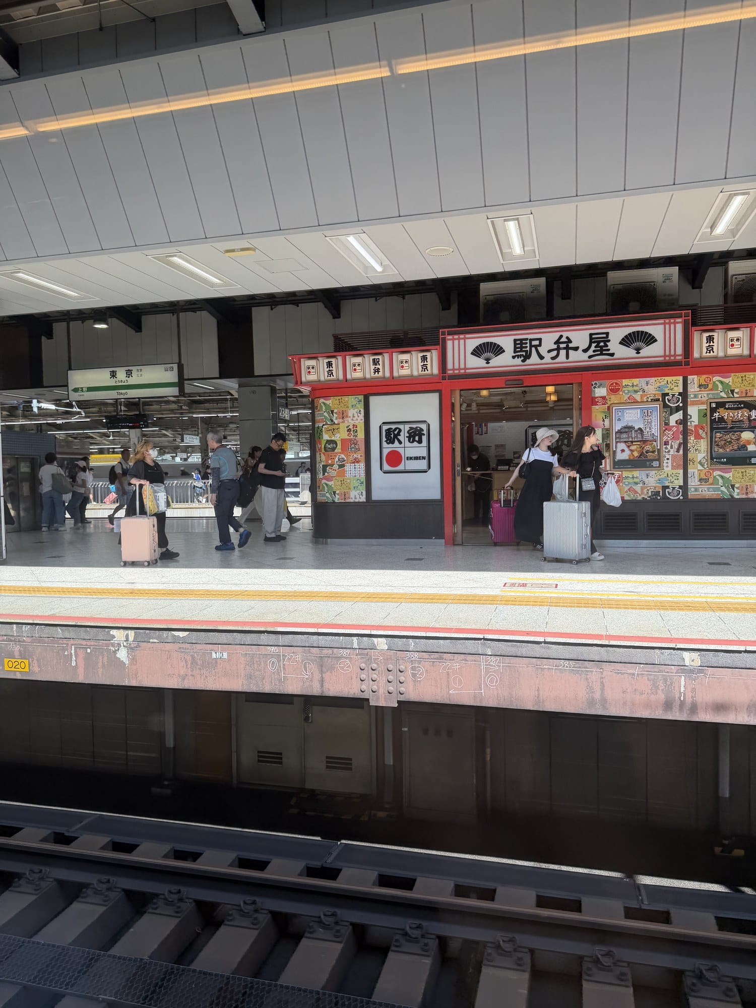 Ekiben bento shop storefront at Tokyo Station with a red facade and EKIBEN signage next to a Tokyo station name board
