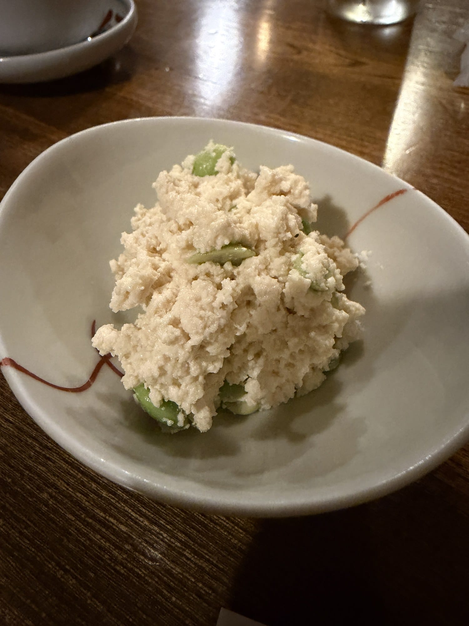 Shira-ae of crumbled tofu with shelled green beans in a white bowl, the otoshi cover dish at an izakaya in Hachinohe, Aomori