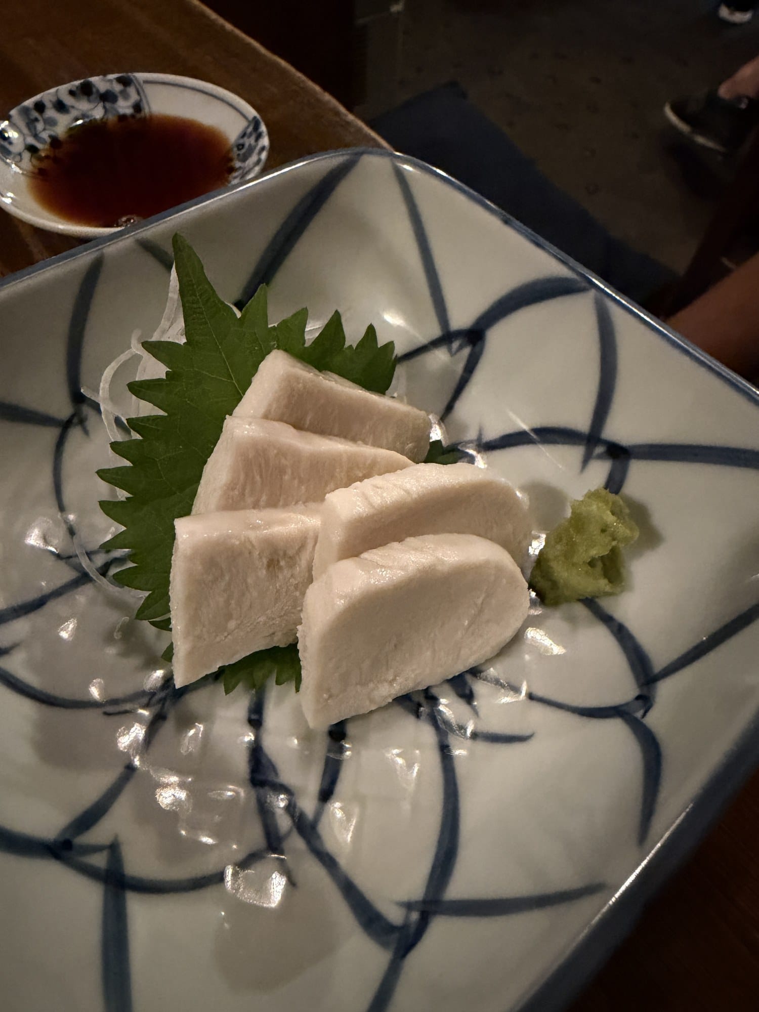 Thick slices of tako no shirako, octopus milt, served cold with wasabi on a shiso leaf at an izakaya in Hachinohe, Aomori