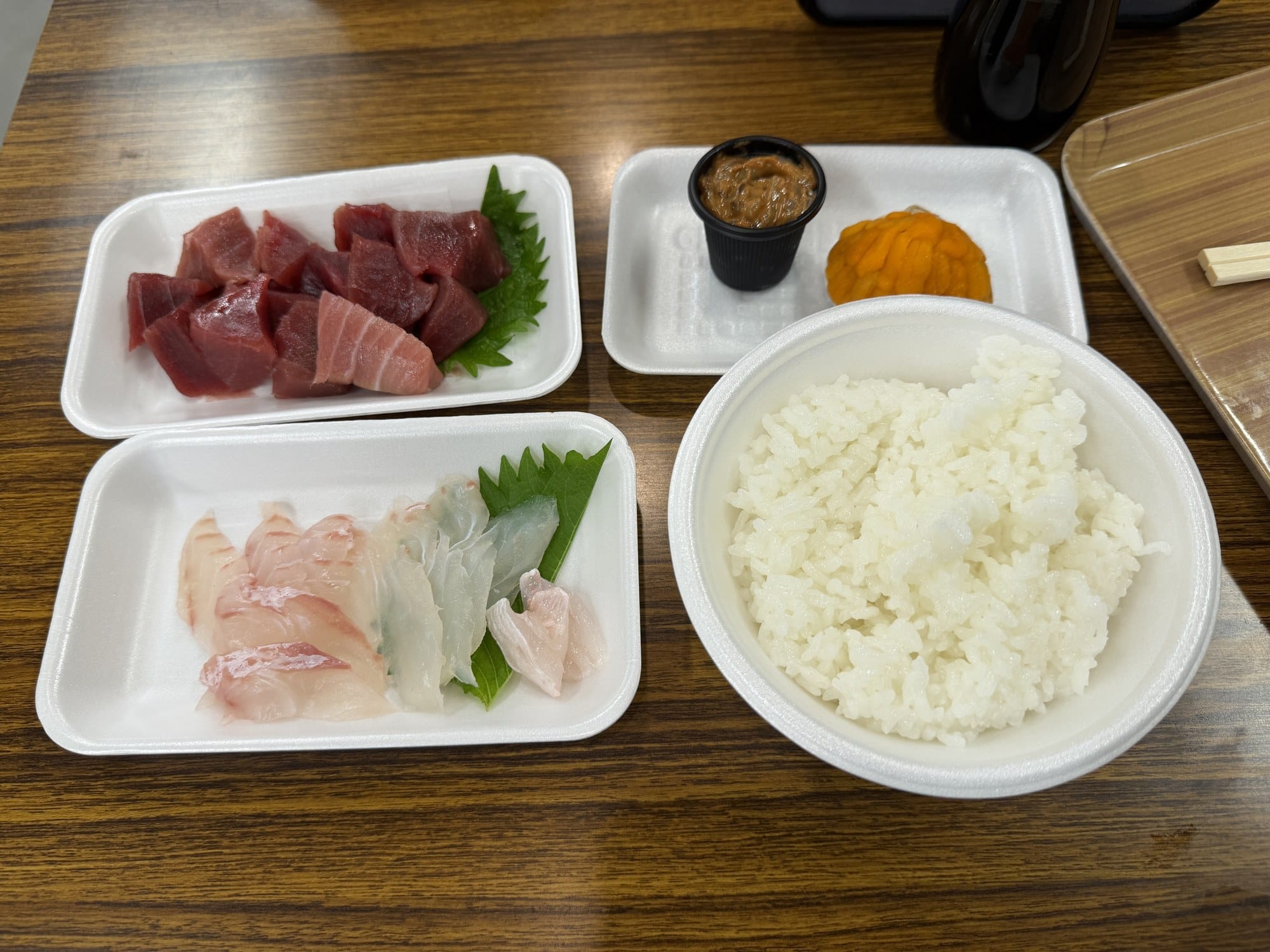 Market breakfast in Hachinohe, Aomori: foam trays of tuna sashimi, two white fish, sea urchin, salted squid and a bowl of rice