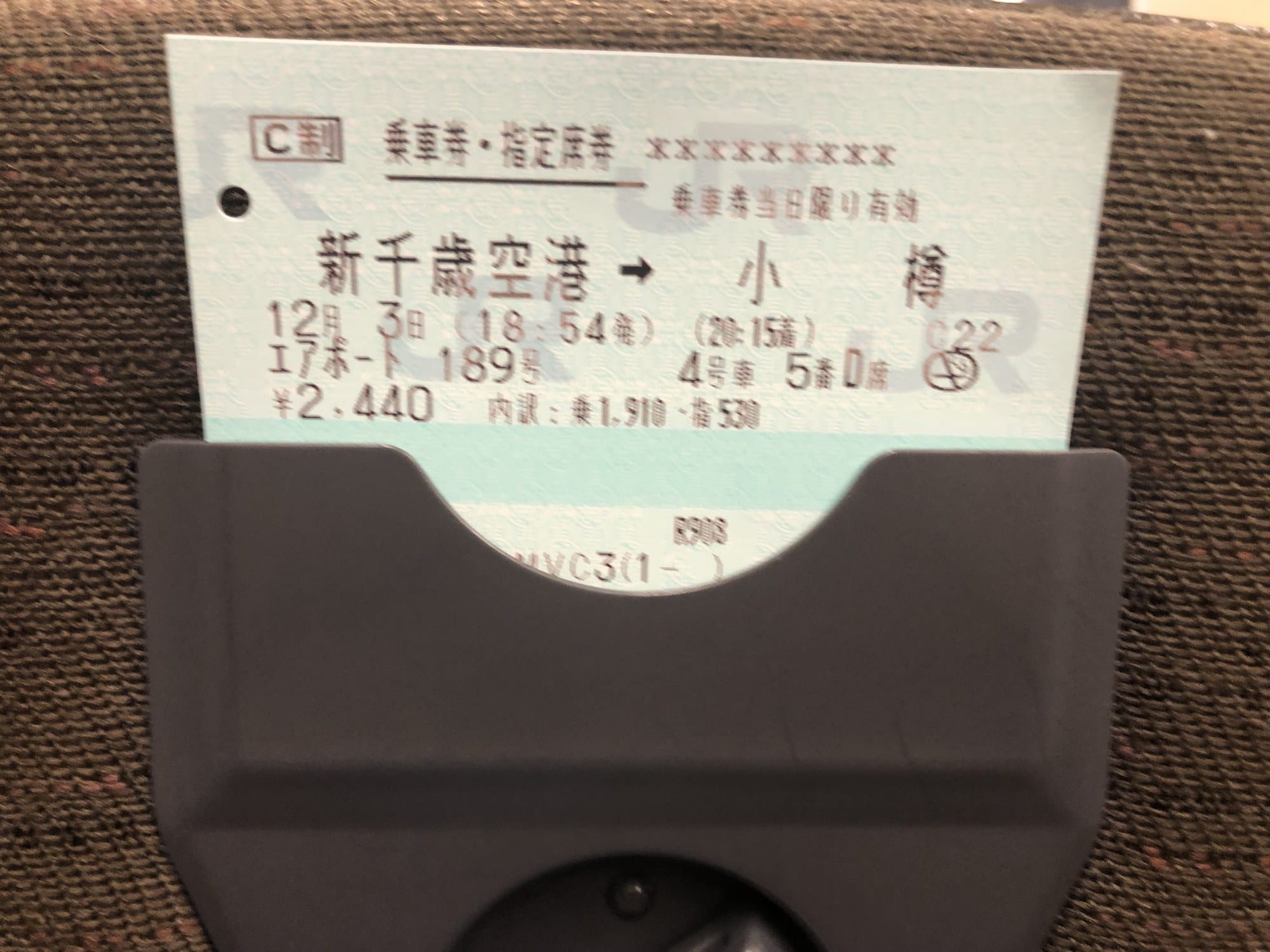 A JR ticket from New Chitose Airport to Otaru slotted into the holder on the seat back