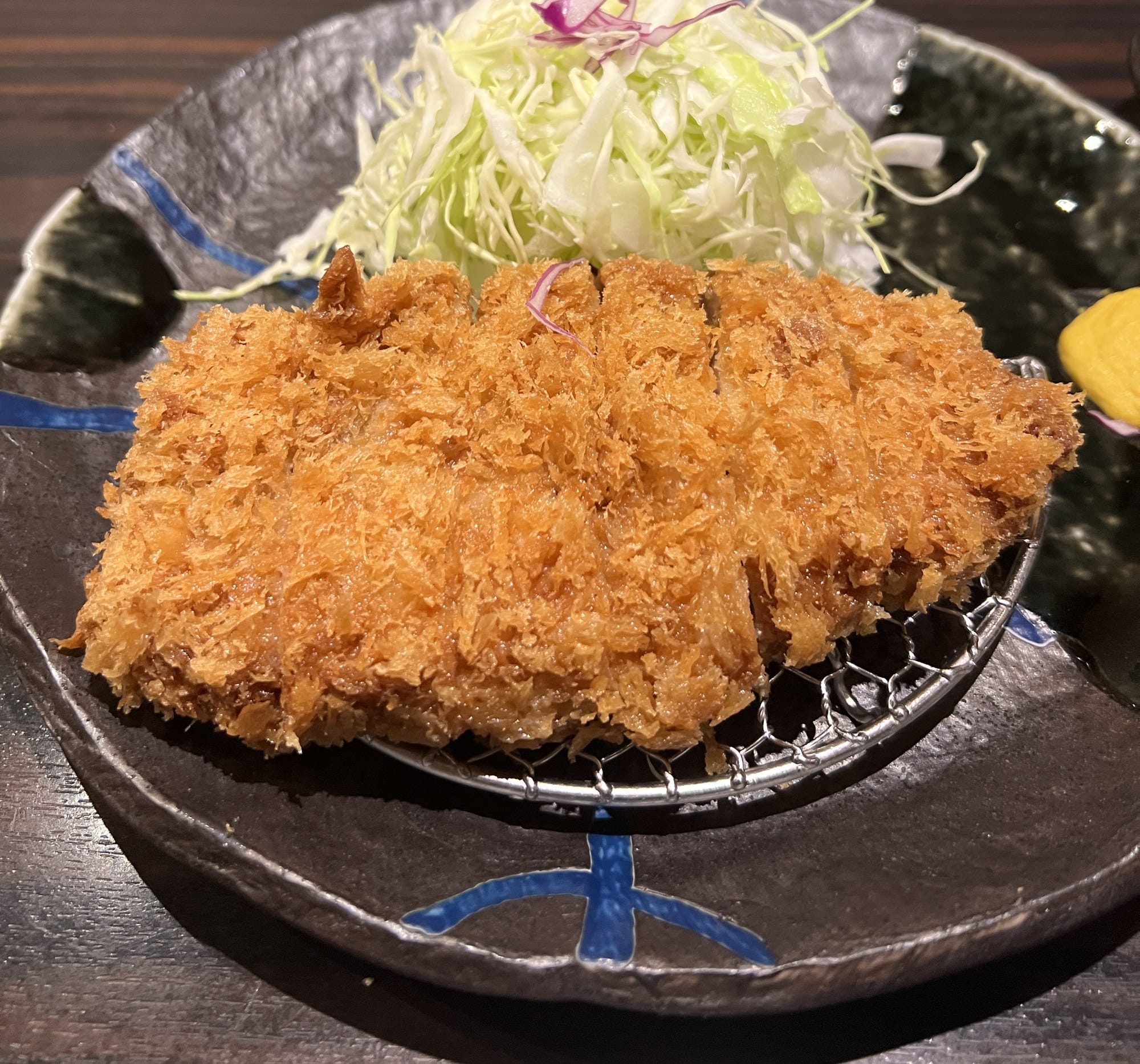 Tonkatsu with shredded cabbage on a black plate at Katsuretsutei in Kumamoto