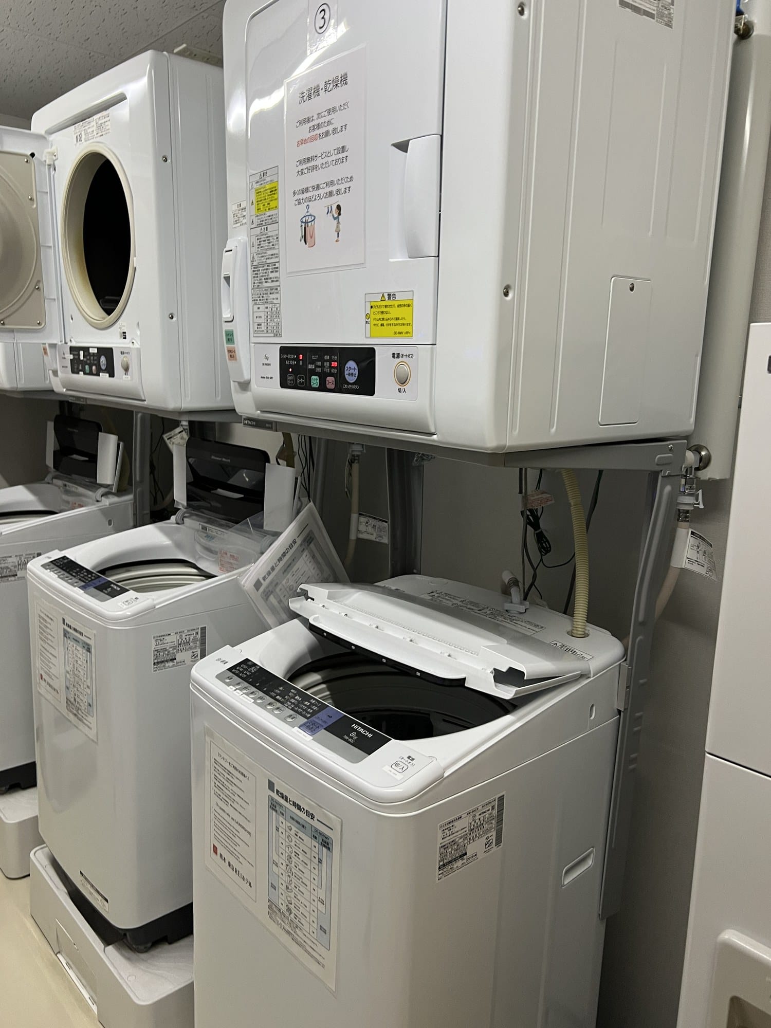 Coin laundry room with stacked washers and dryers at Kumamoto Tokyu REI Hotel