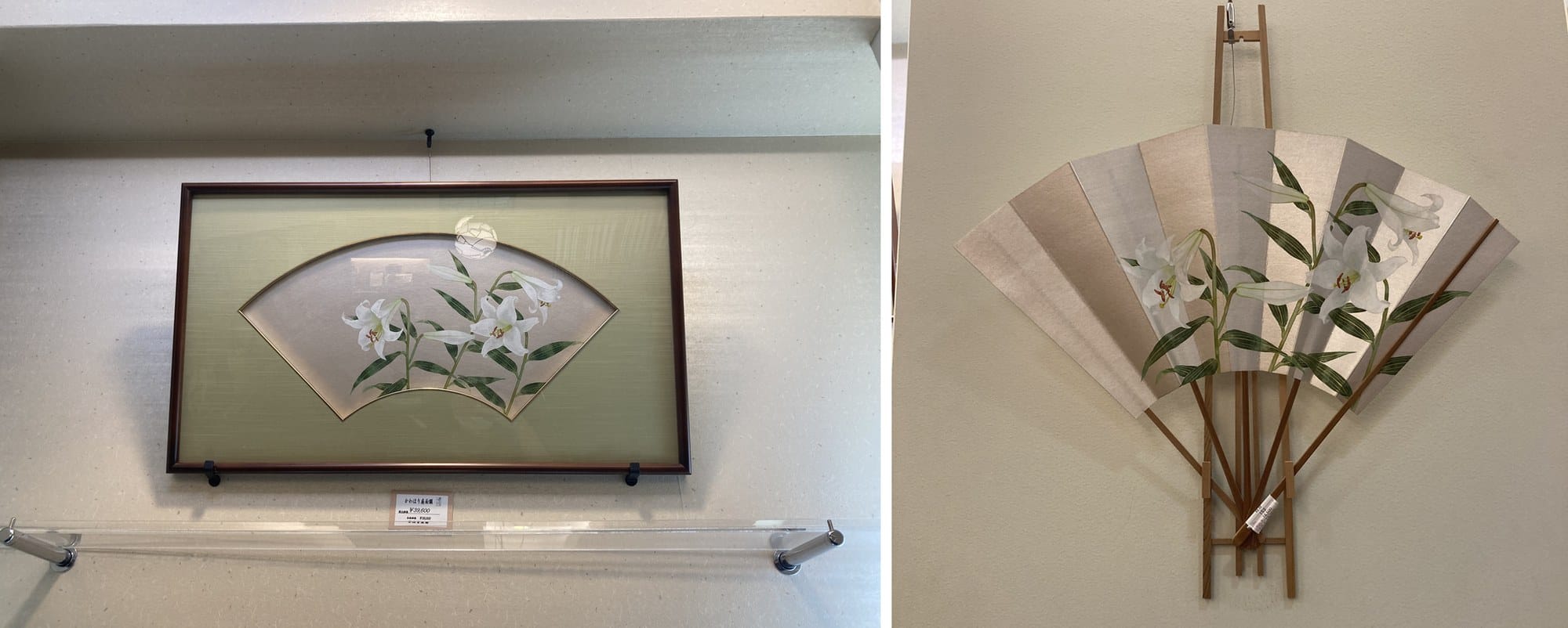A Kyoto fan mounted in a wide frame on a wall, and a silver fan with painted lilies open on a wooden stand