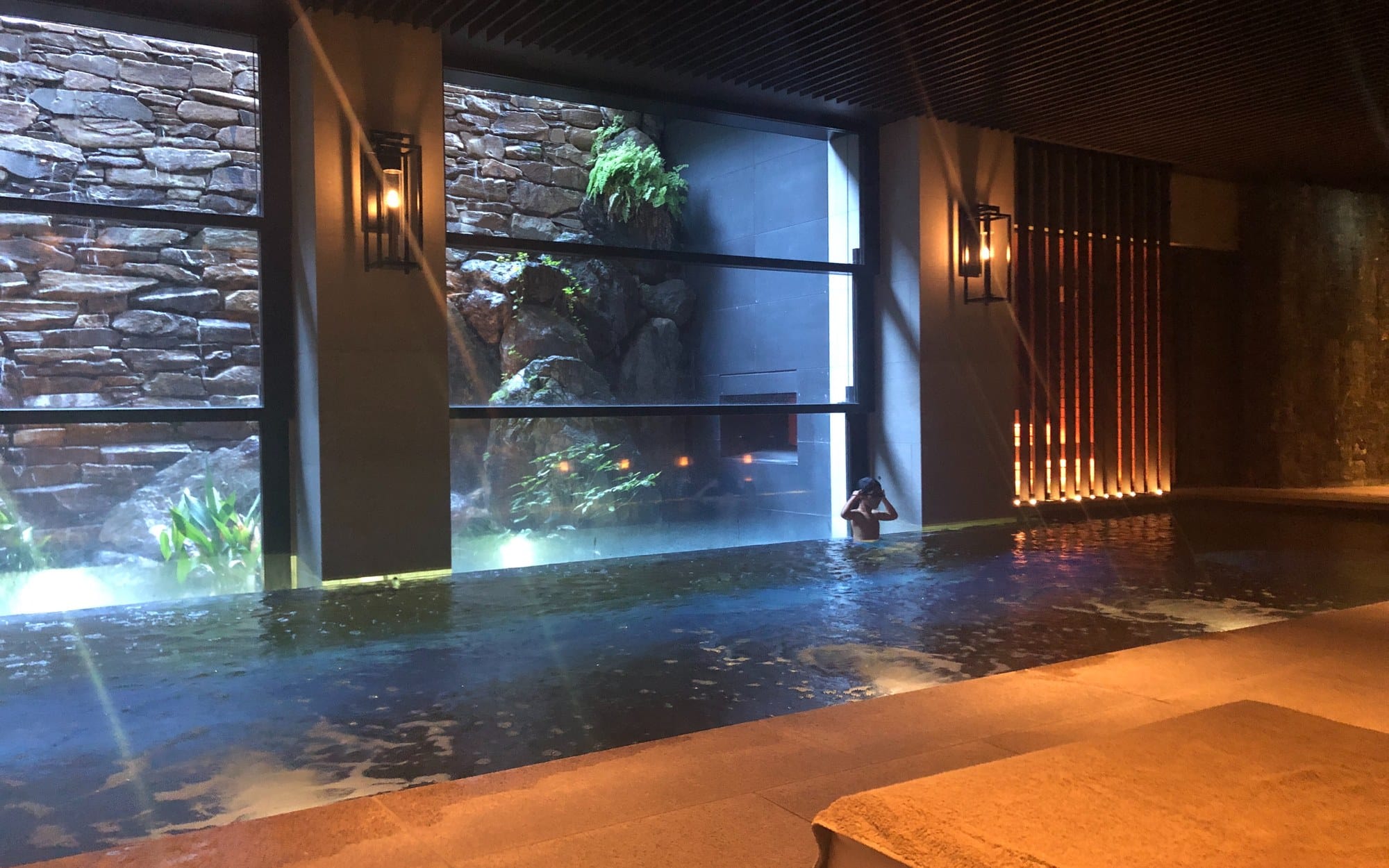 The indoor pool at the Ritz-Carlton Kyoto, lit warm against a dry-stone wall