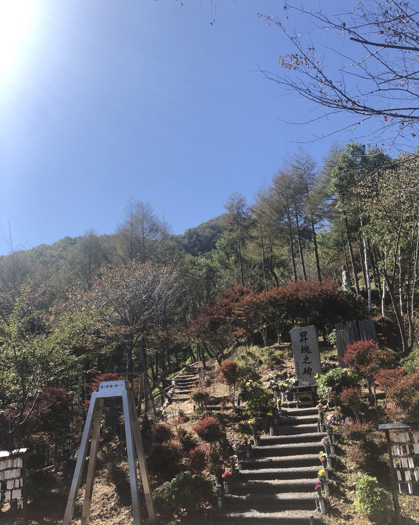 The Shokon-no-Hi stone marker on Osutaka Ridge with steps, flowers and rows of wooden sotoba tablets