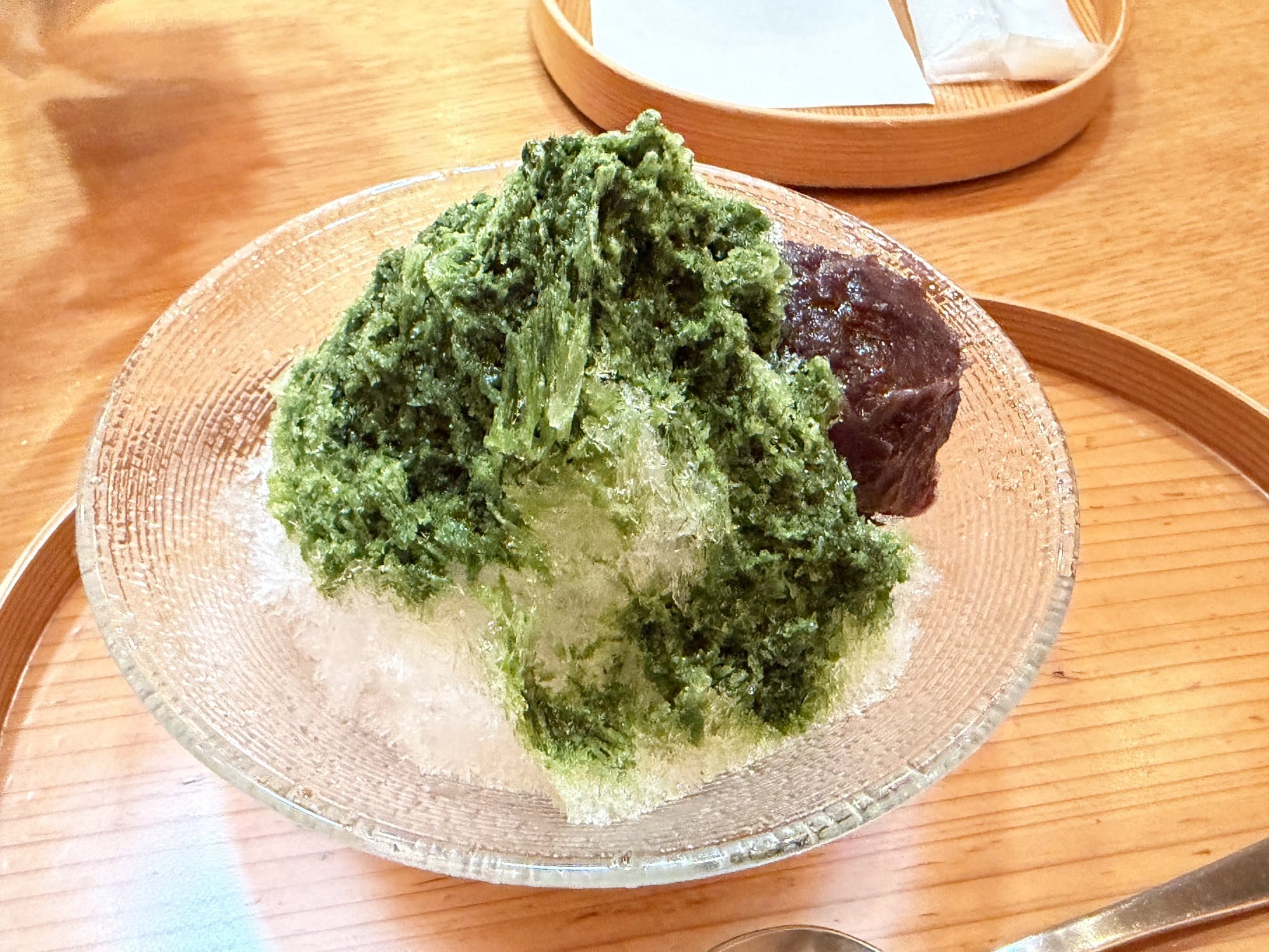 Shaved ice with matcha syrup at Toraya Kobo, served on a glass dish with a mound of red bean paste beside it