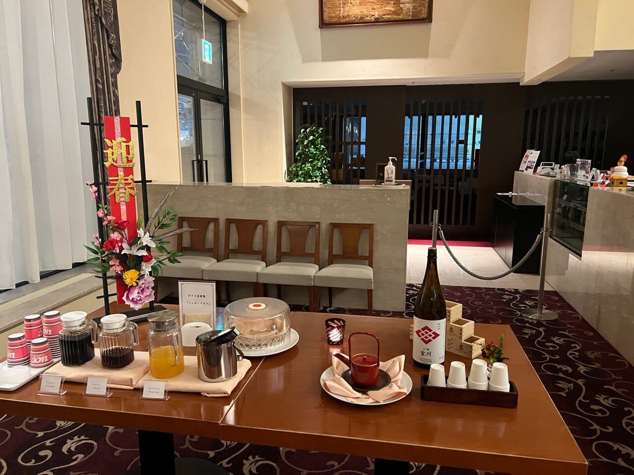 First-floor lounge at Authent Hotel Otaru with a self-serve coffee and juice table and a row of seats by reception