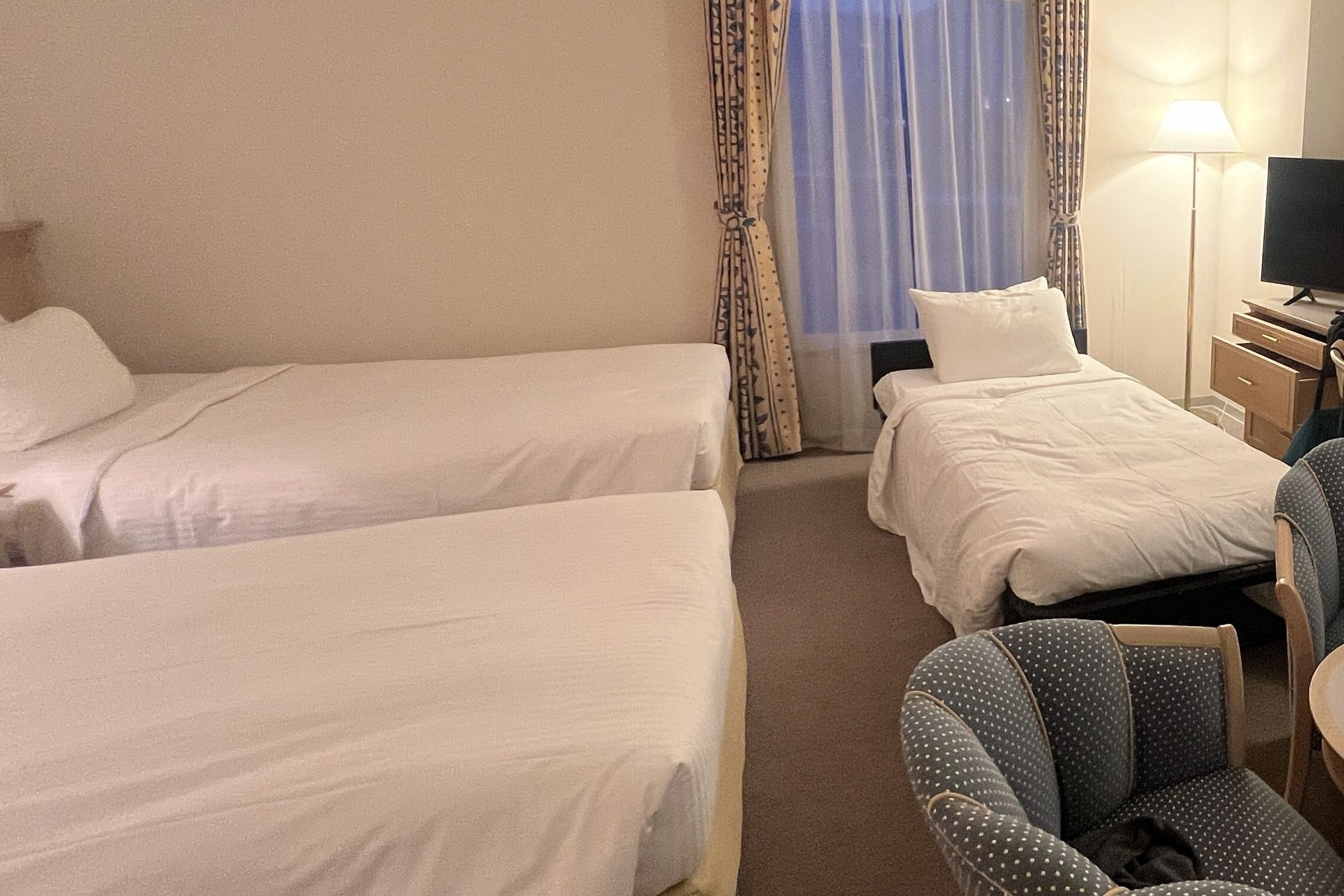 Two fixed twin beds and a third, lower extra bed on a separate dark metal frame by the window of a room at Authent Hotel Otaru