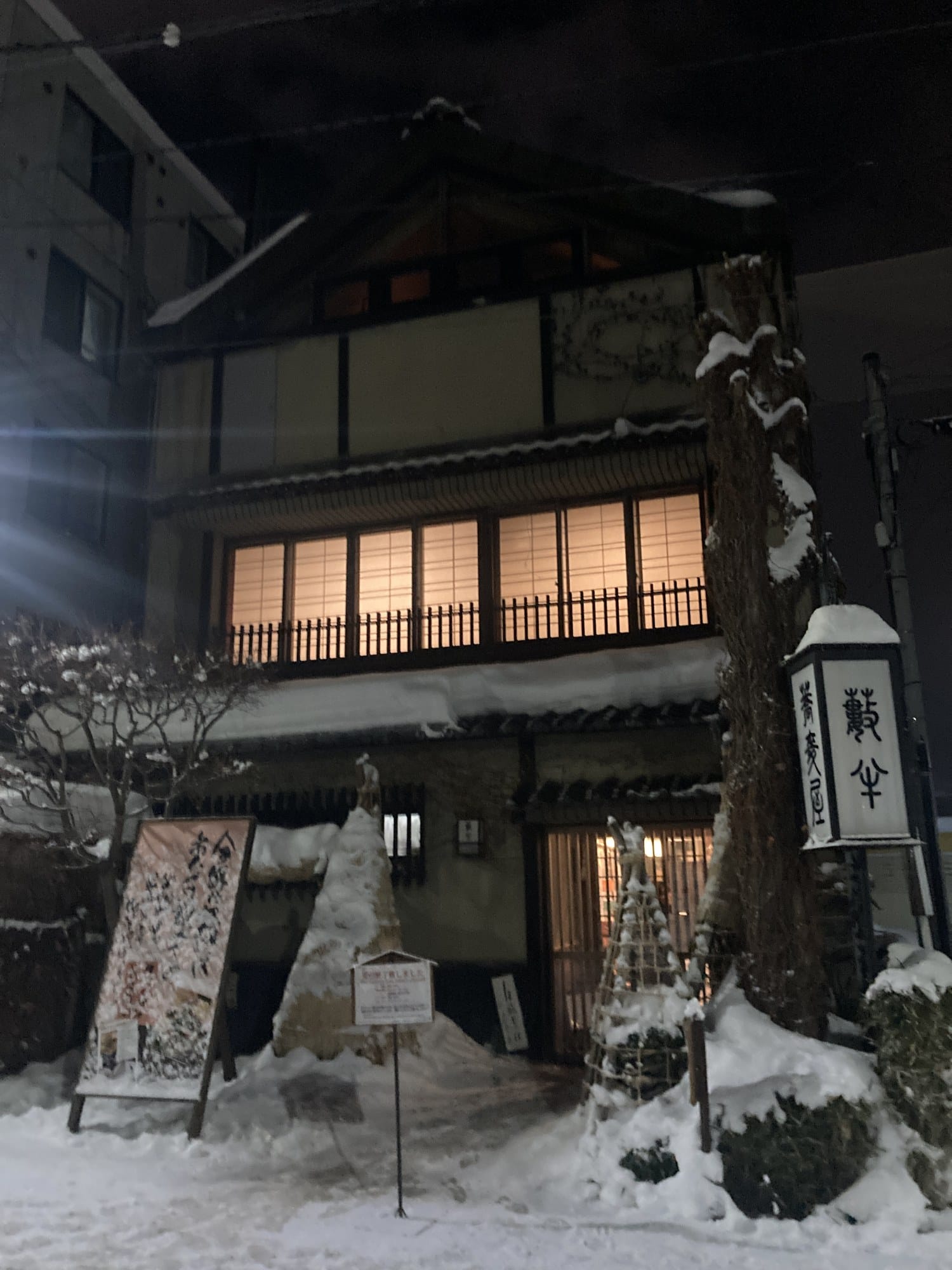 A lit paper lantern outside a soba restaurant in Otaru on a snowy night