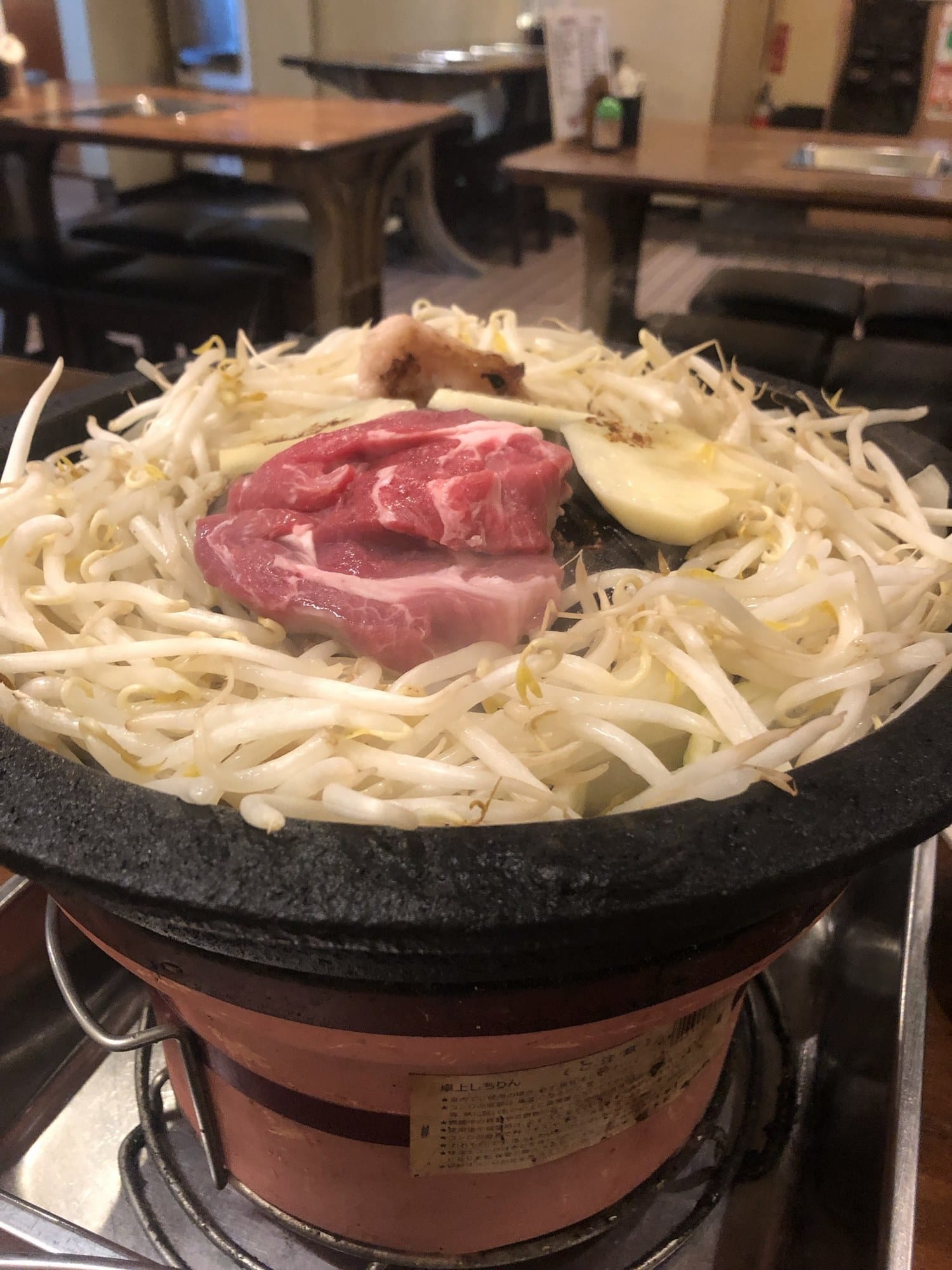 A jingisukan pot on a tabletop burner with meat, bean sprouts and onion at Kitatogarashi in Otaru