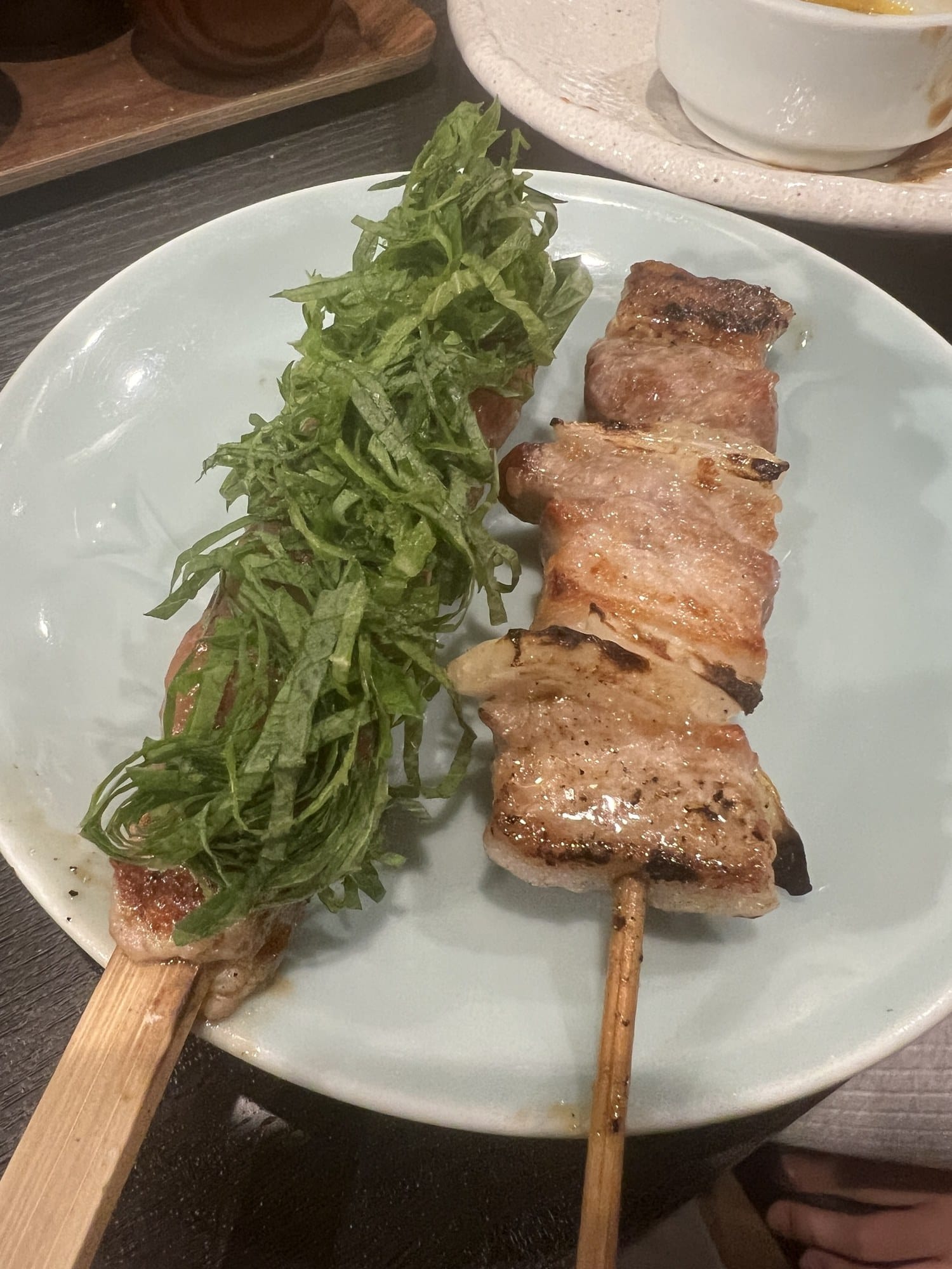 Two grilled pork skewers, one topped with shredded shiso, at Kushiyaki Ryo in Otaru