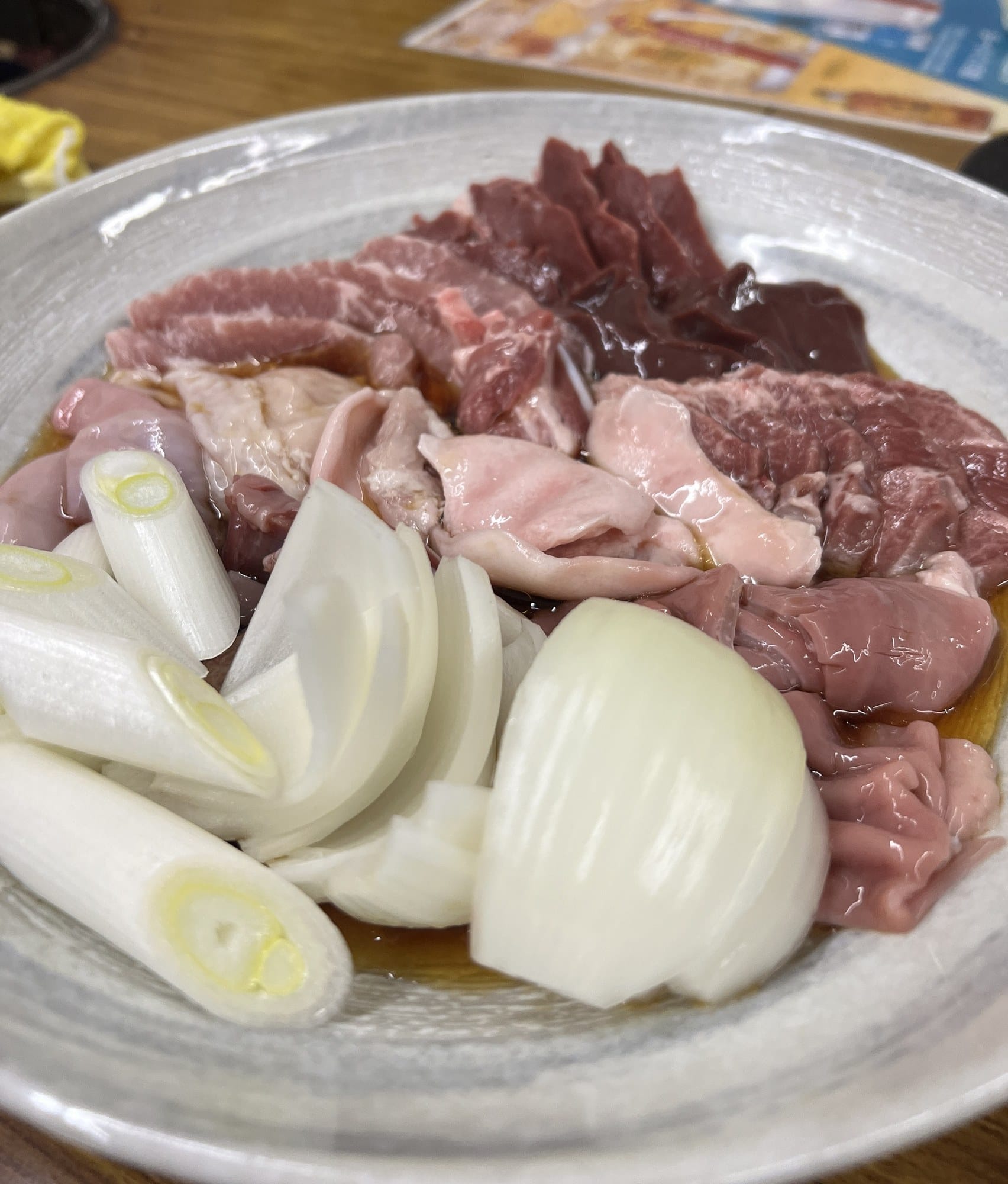 A platter of tare-marinated raw horumon with sliced onion and leek, ready for the grill, at Kinta no Kinta in Otaru