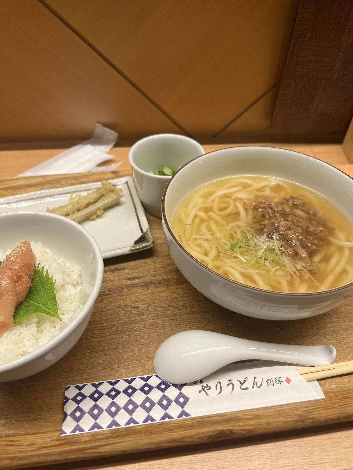 Hakata udon set meal on a wooden tray with mentaiko rice, tempura, and broth