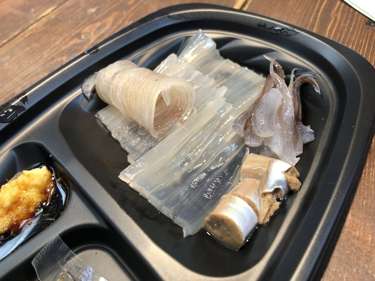 Plate of fresh ika sashimi (ikizukuri squid) with tentacles still curling, served with ginger and soy sauce