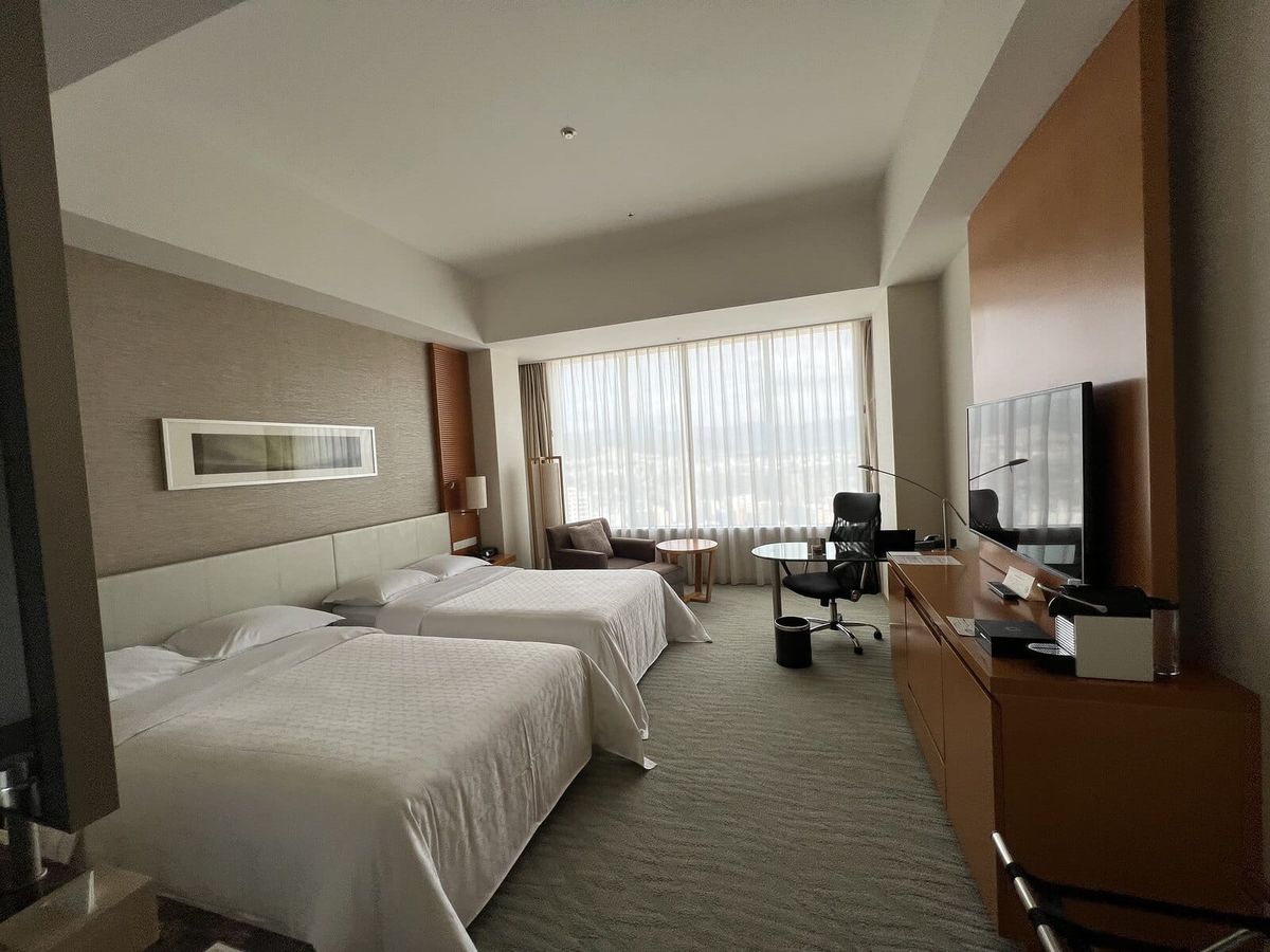 Twin hotel room in Hiroshima with large windows and a work desk