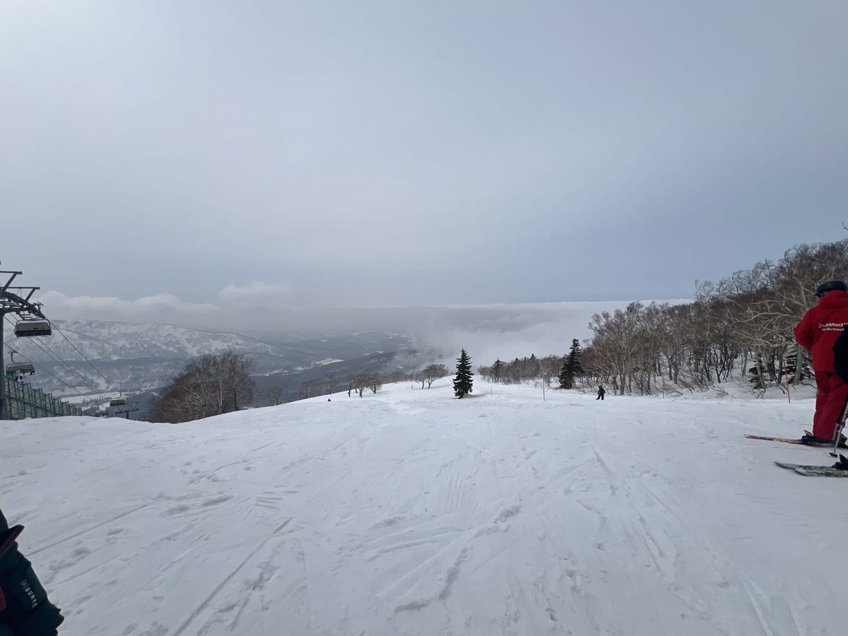 A Club Med staff member in the red uniform on a Kiroro piste overlooking the valley
