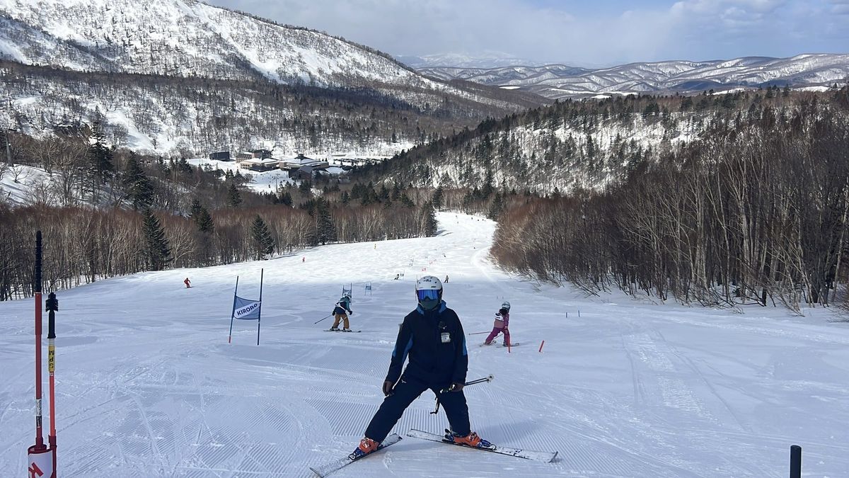Skier on a race-training lane at Kiroro Snow World with the resort base and valley below