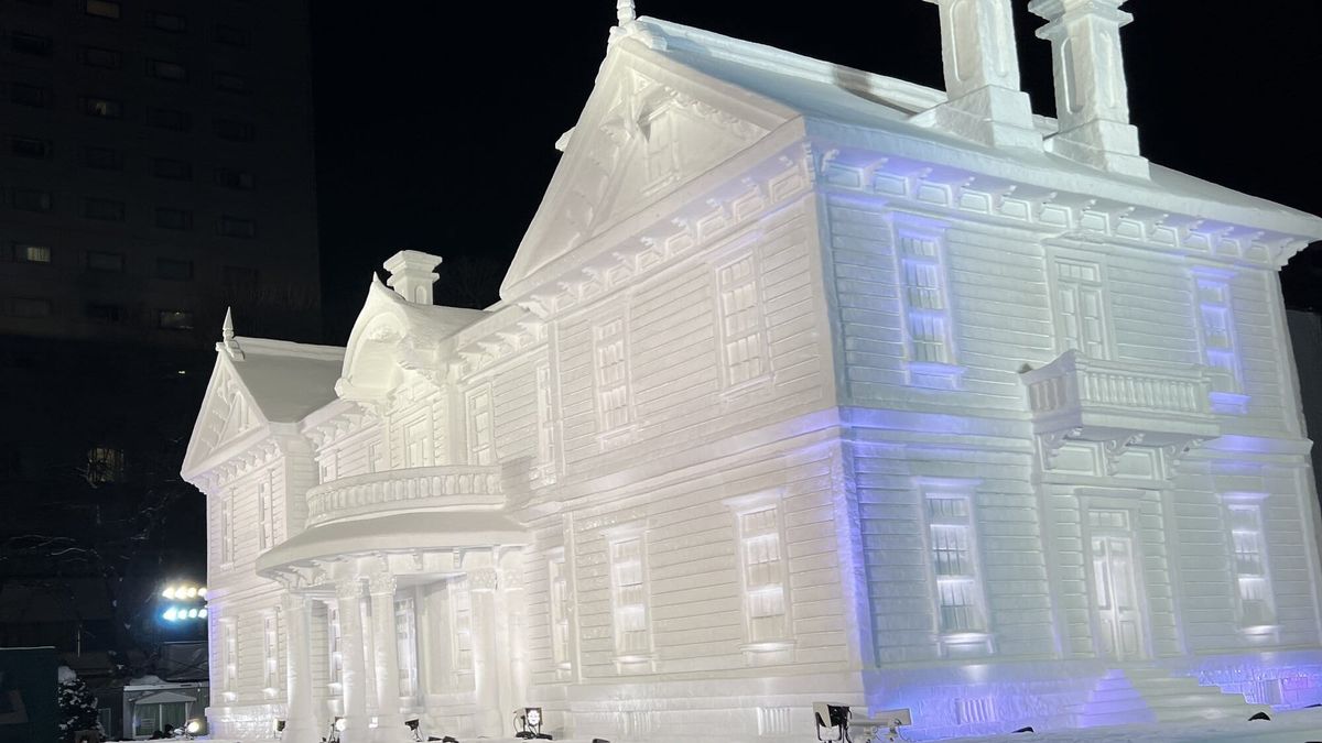 Large snow sculpture of a historic Western-style building illuminated at night in Odori Park during the Sapporo Snow Festival