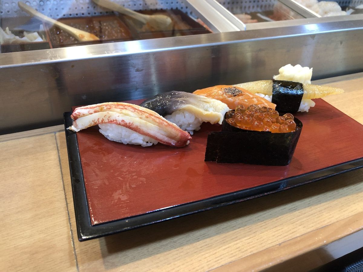 Assorted Otaru sushi nigiri including snow crab, scallop, salmon, and salmon roe on a red lacquer tray