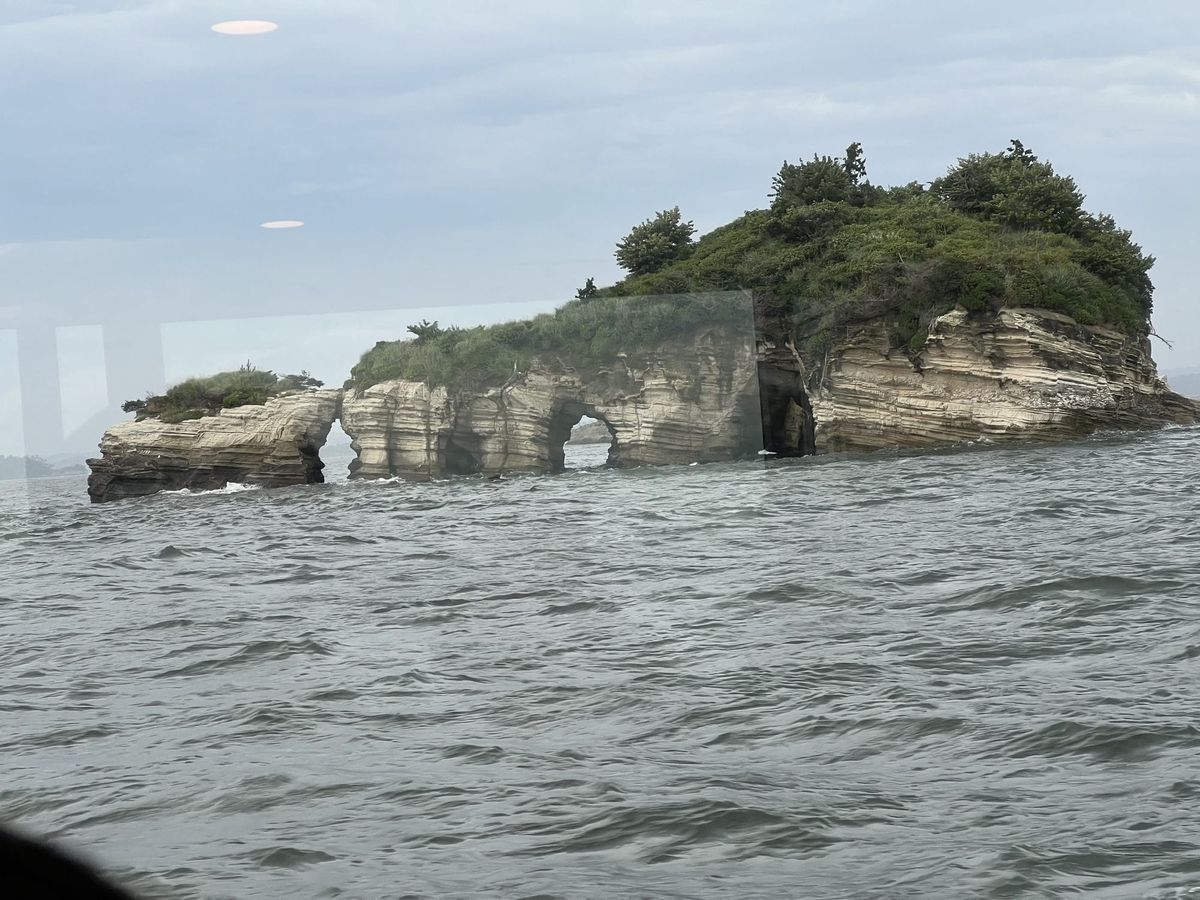 Rocky limestone island with natural sea arches rising from Matsushima Bay, viewed from the water
