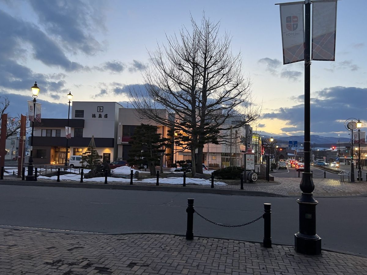 The street in front of JR Yoichi Station at dusk, with lampposts and banners