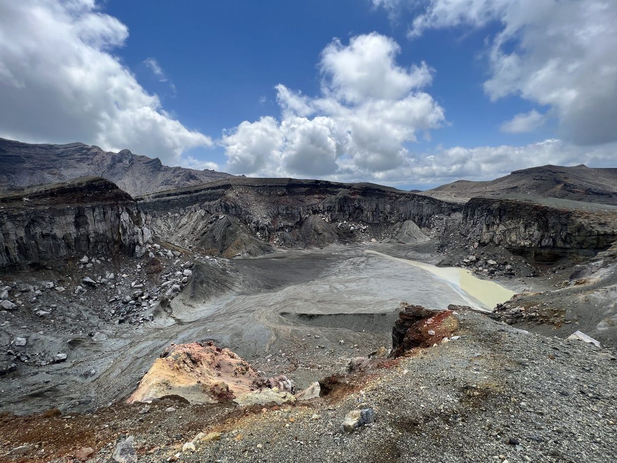 Nakadake crater basin at Mount Aso with a milky crater lake under a blue sky