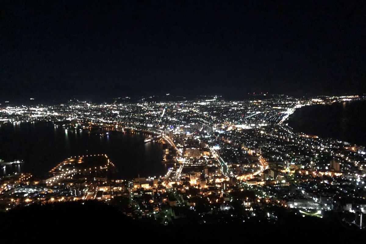The night view from Mount Hakodate, with the city lights forming a narrow waist between two dark bays