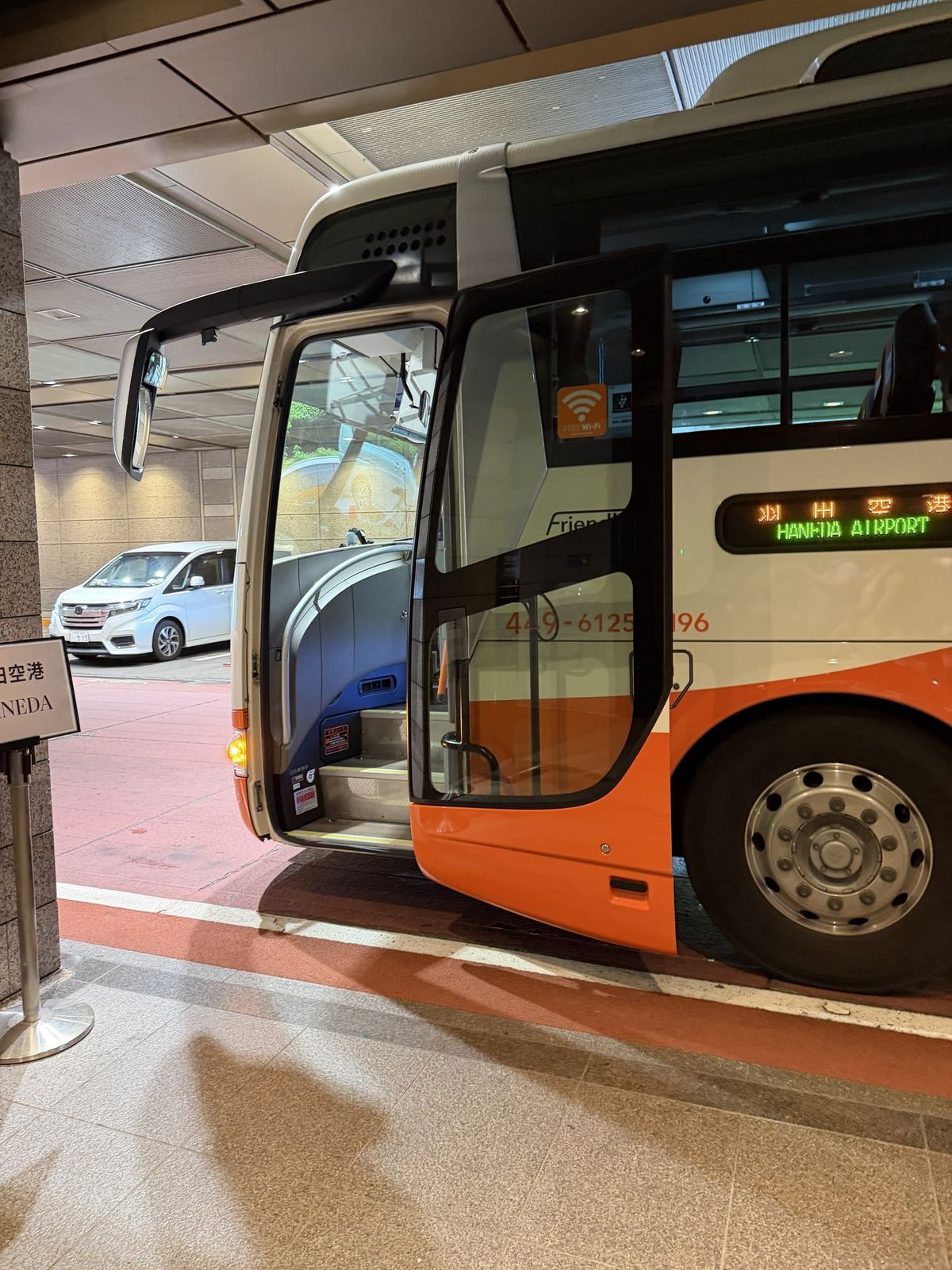 Airport limousine bus with a Haneda Airport destination sign at a hotel entrance