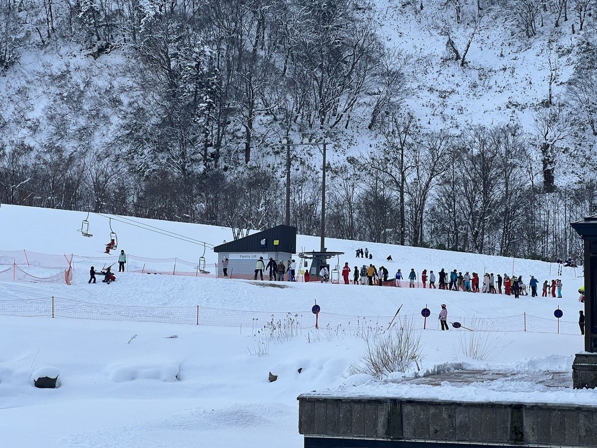 Queue of skiers and ski school groups at the Family Lift at the base of Kiroro