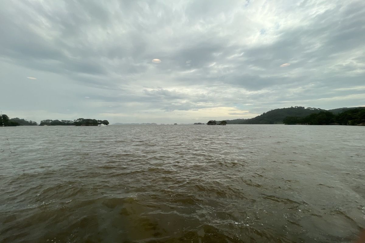 Matsushima Bay from water level, with pine-topped islands scattered across the water under a heavy grey sky