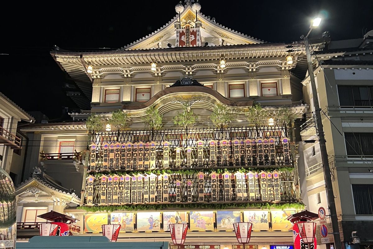 The illuminated facade of the Minamiza kabuki theatre at Shijo-Ohashi in Kyoto at night, with buses passing in front