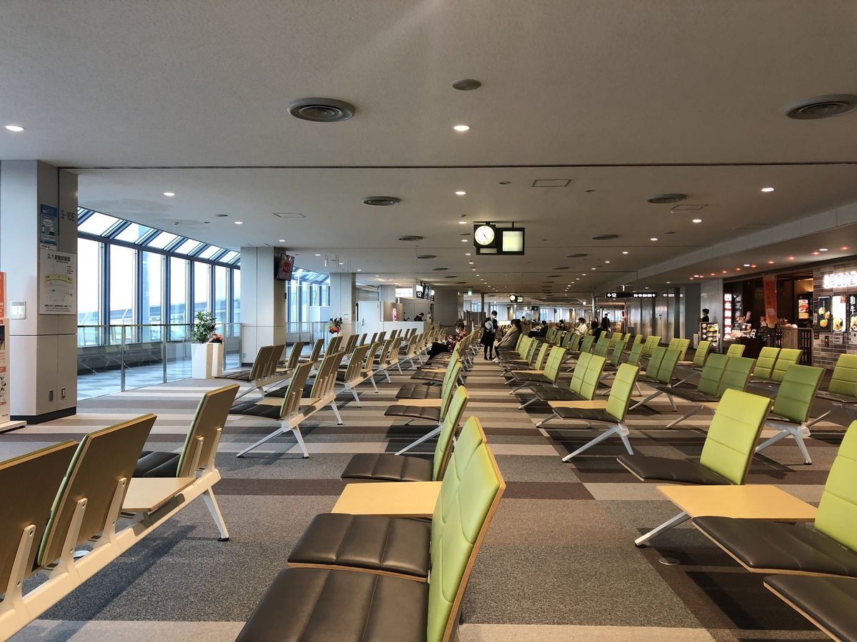 The departure lounge at New Chitose Airport, with rows of seating and table-equipped seats near the gates