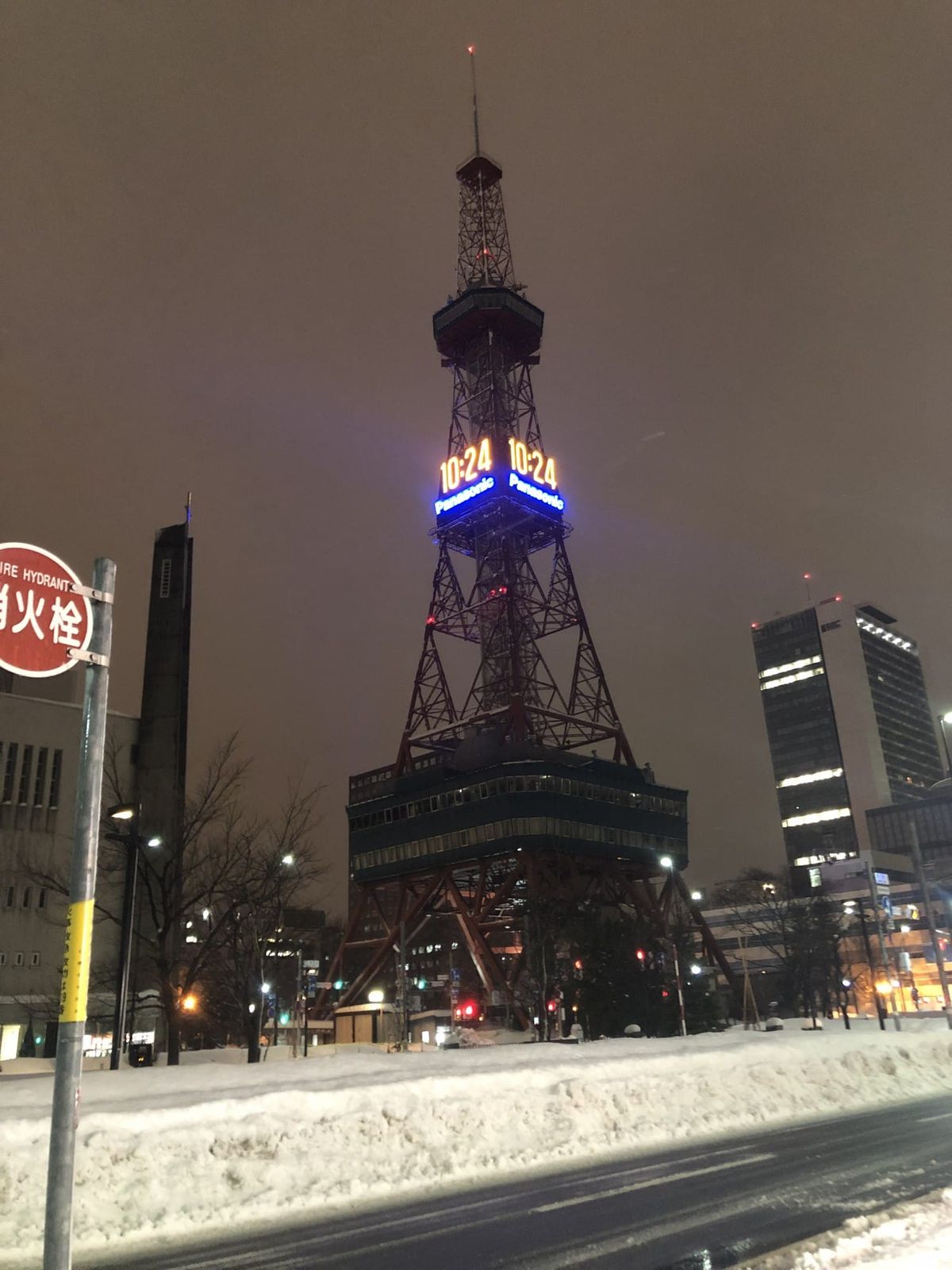 Sapporo TV Tower lit at night above snow-cleared streets in central Sapporo