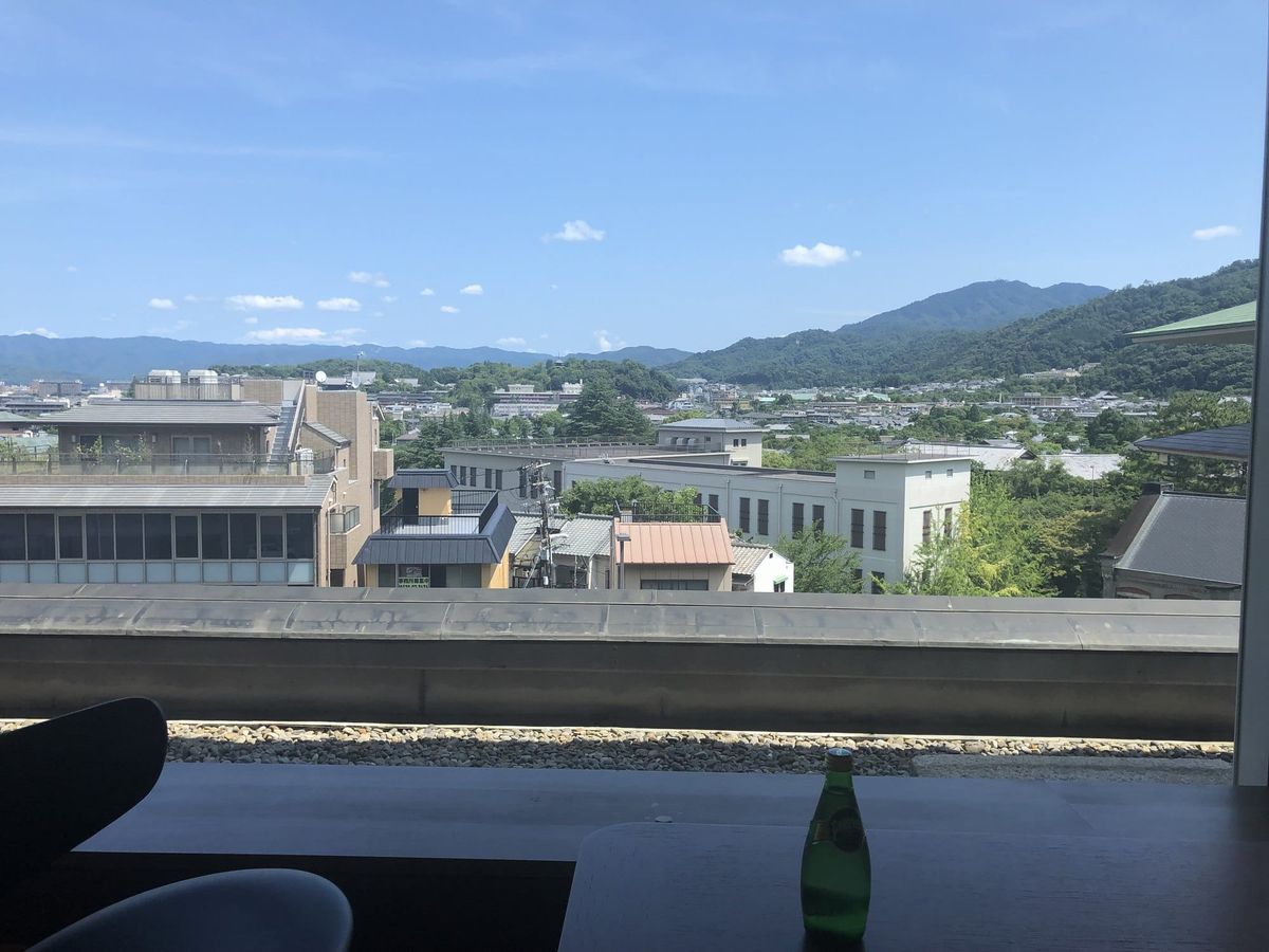 The view from the club lounge counter at The Westin Miyako Kyoto over tiled rooftops towards the wooded Higashiyama hills, wi