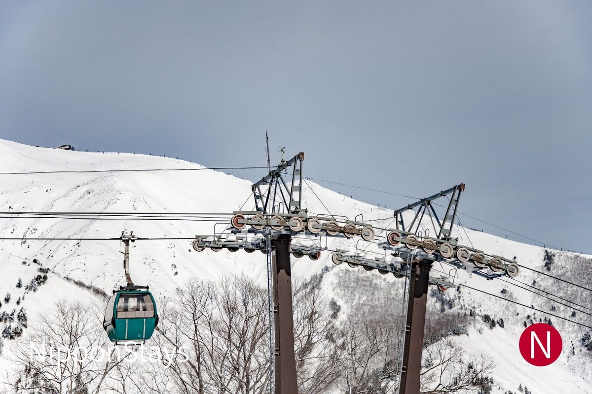 A gondola cabin climbing above a snow-covered ski area