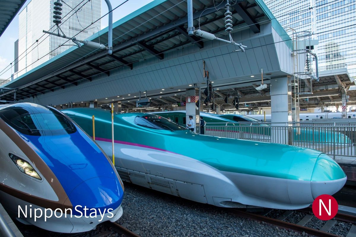 A Hokuriku Shinkansen E7 series train standing at a platform